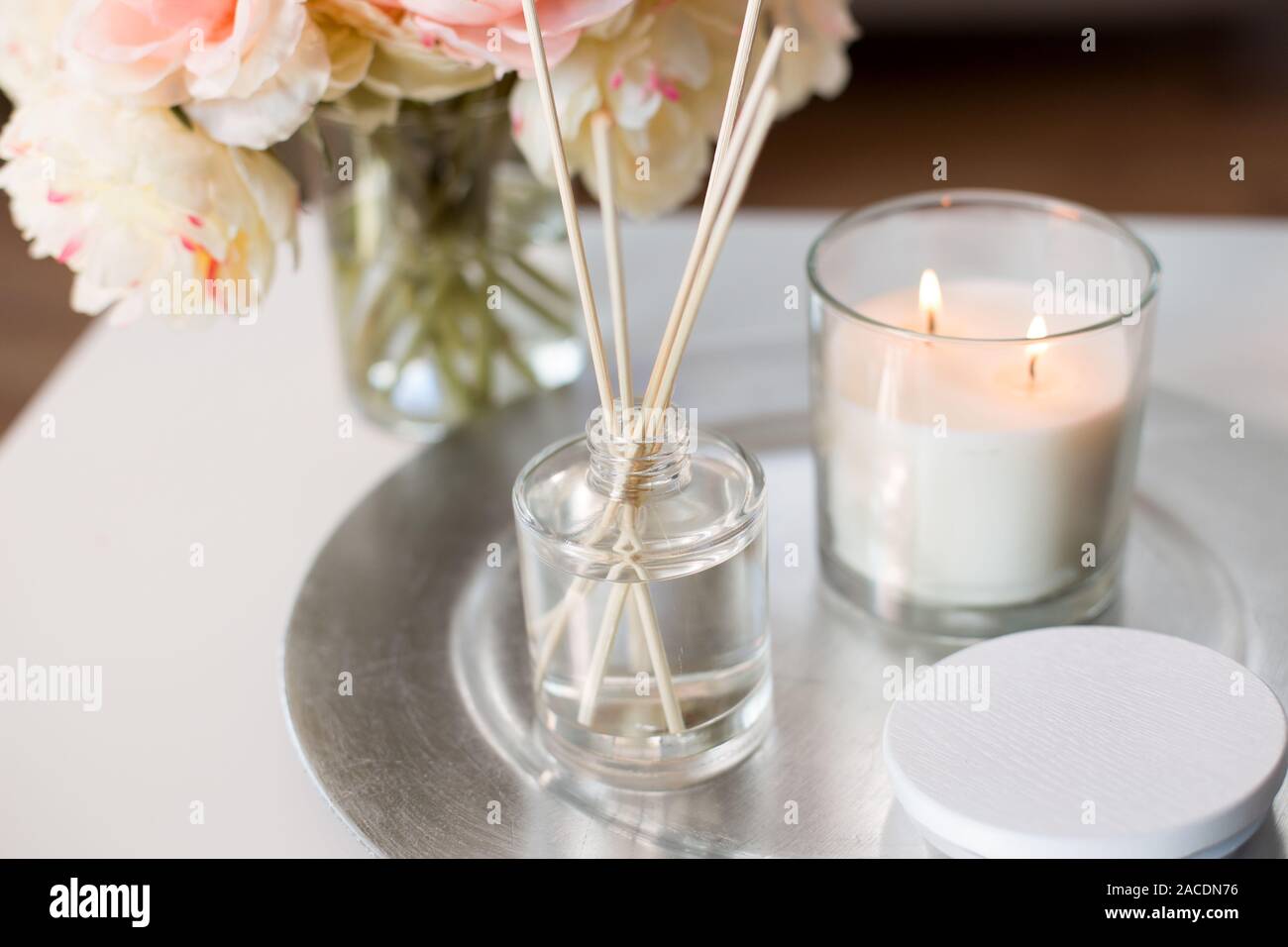 Aroma diffusore reed, candela e fiori sul tavolo Foto Stock