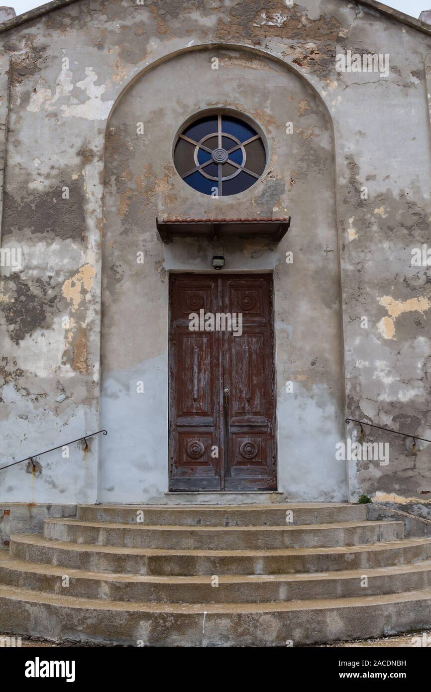 Scale fino alla porta di ingresso di una vecchia chiesa. Finestra di  cerchio sopra la porta di legno. La facciata a spiovente. Argentiera,  Sardegna, Italia Foto stock - Alamy