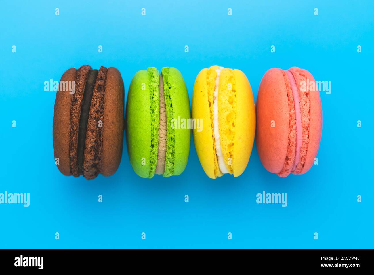 Amaretti colorati su sfondo blu. Bright rainbow i biscotti con la crema. Foto Stock