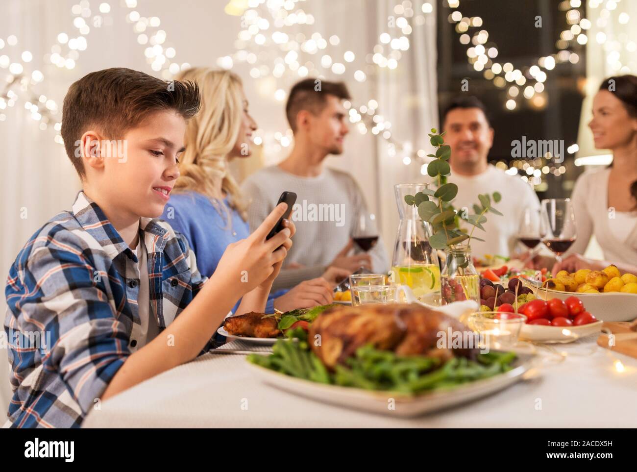 Ragazzo con smartphone a cena in famiglia party Foto Stock