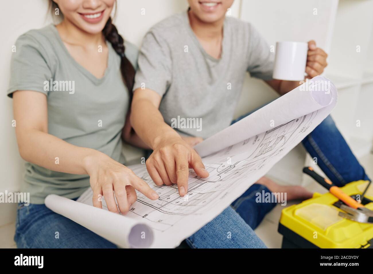 Close-up di immagine sorridente coppia giovane a bere caffè e discutere il piano di costruzione della loro nuova casa Foto Stock
