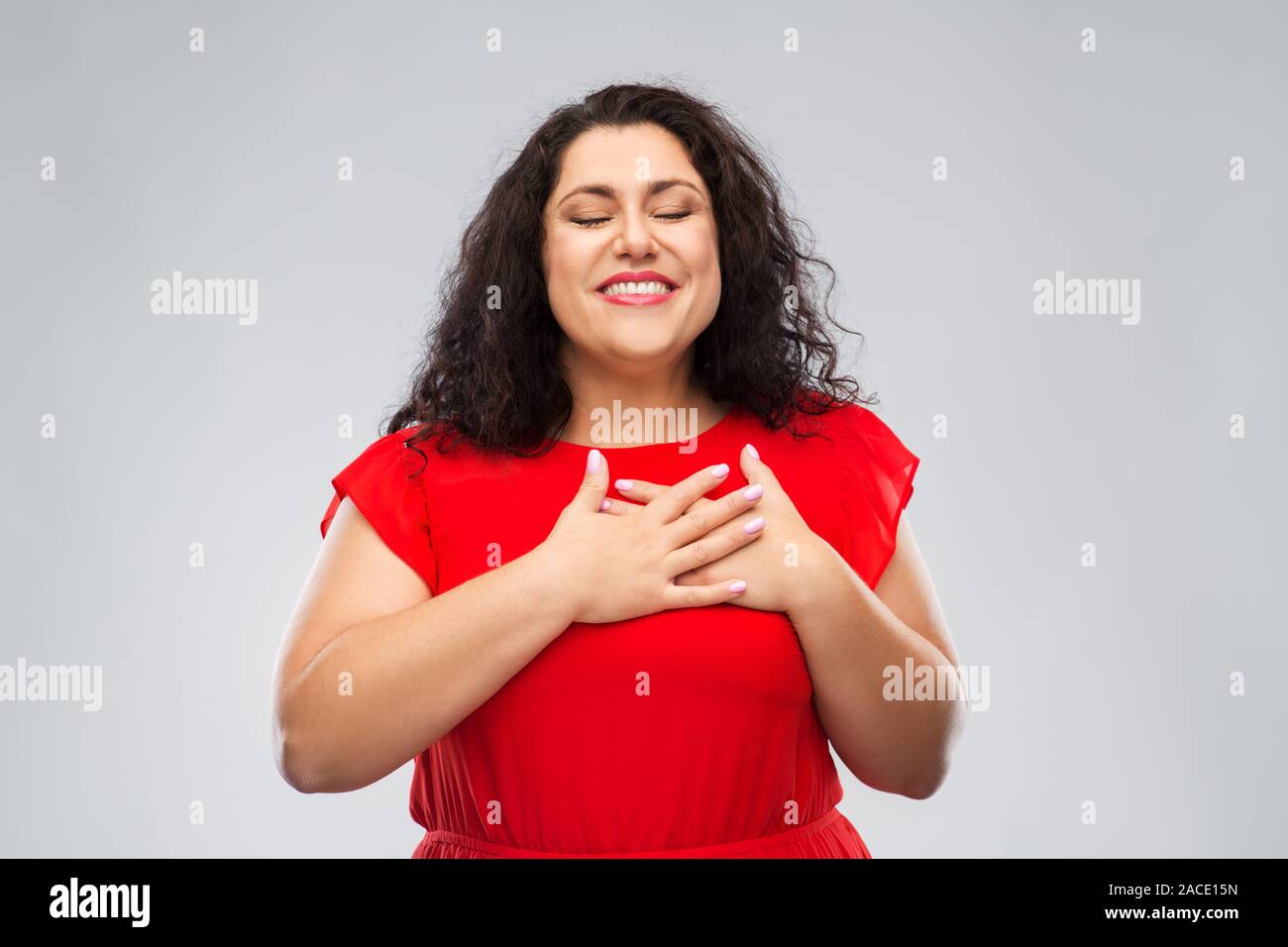 Donna felice tenendo le mani sul petto o cuore Foto Stock