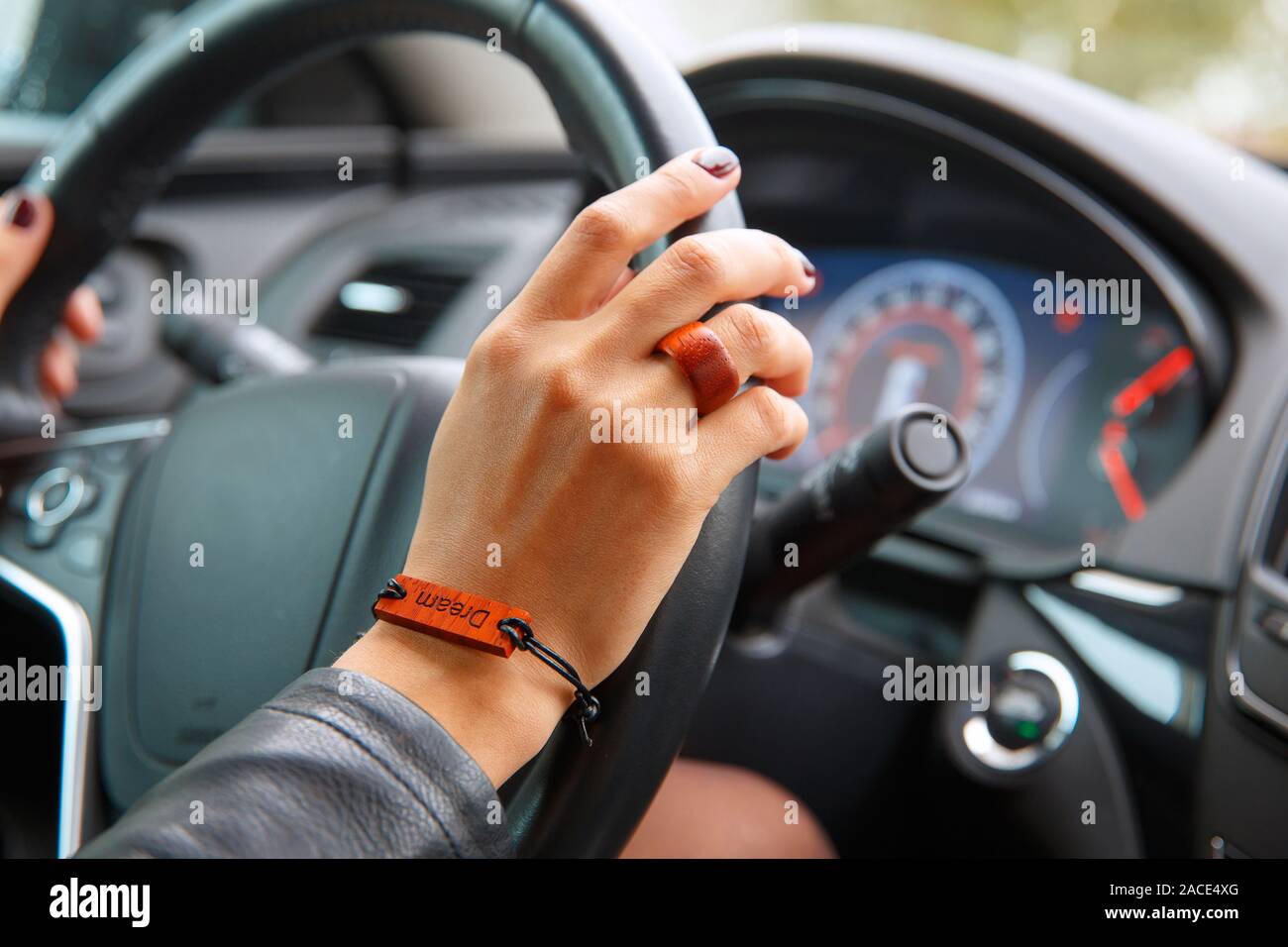 Concetto di scatto: ragazza s le mani sul volante di un automobile, un bracciale con il sogno di iscrizione sulla sua mano. Foto Stock