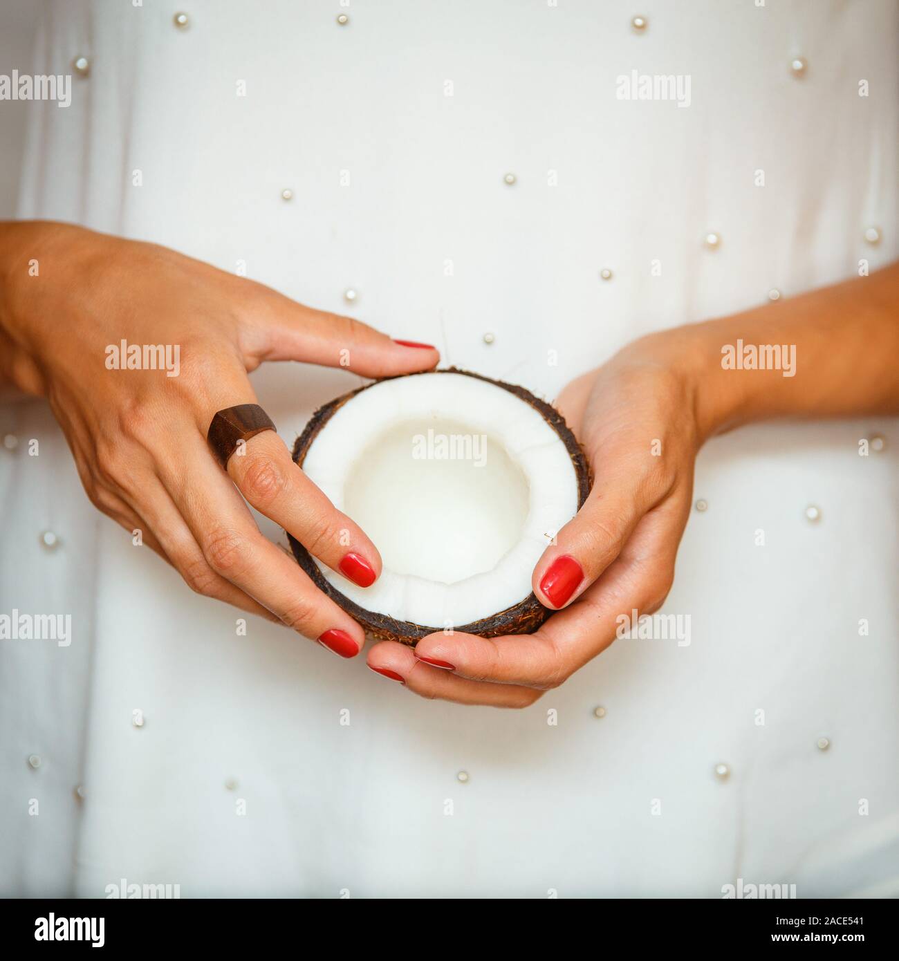 Le mani di una giovane donna che mantiene una mezza noce di cocco. Il mangiare sano concetto Foto Stock