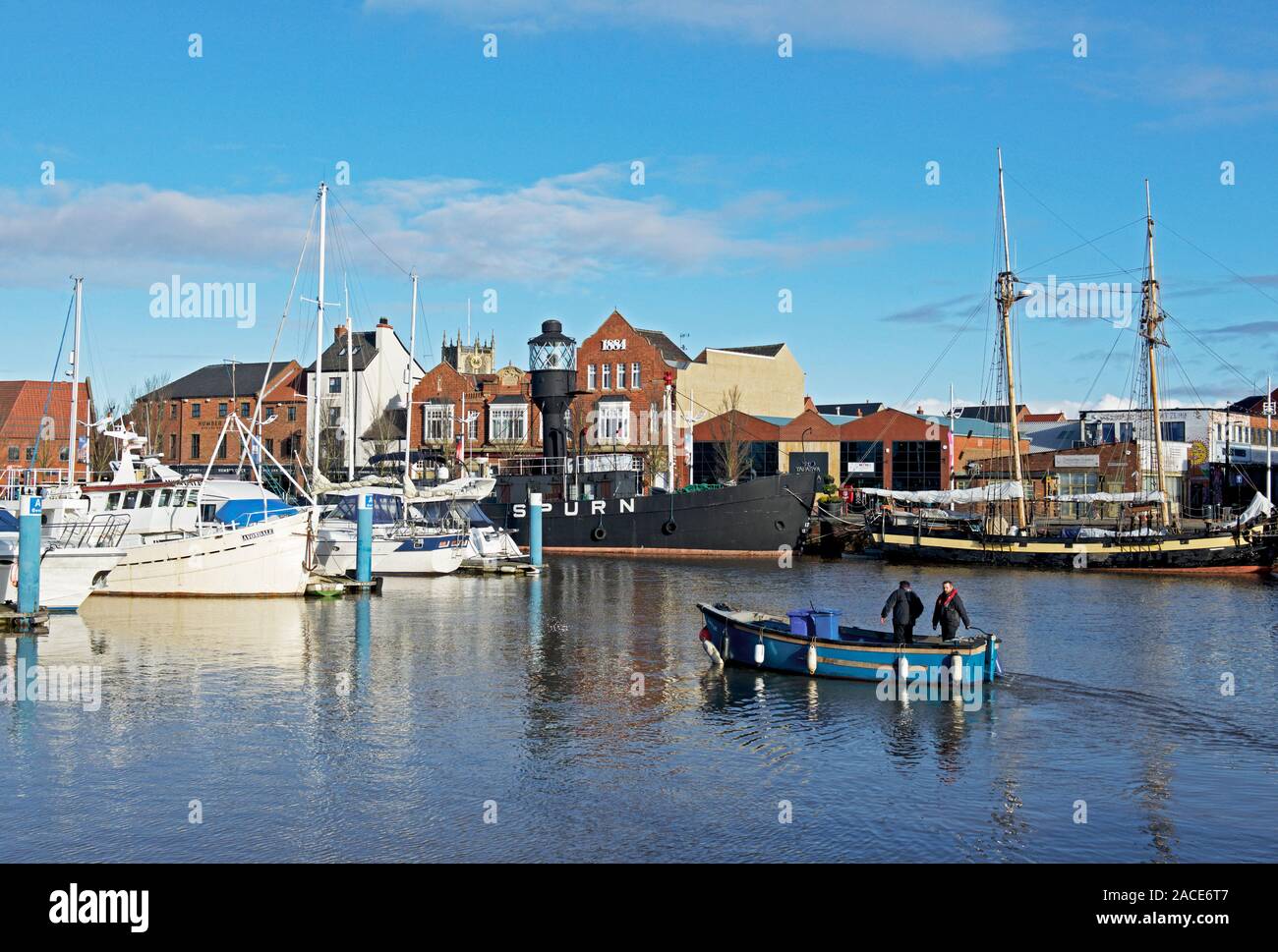 Due uomini in una piccola imbarcazione, sollevamento driftwood e lettiere fuori della marina, Hull, East Yorkshire, Inghilterra, Regno Unito Foto Stock