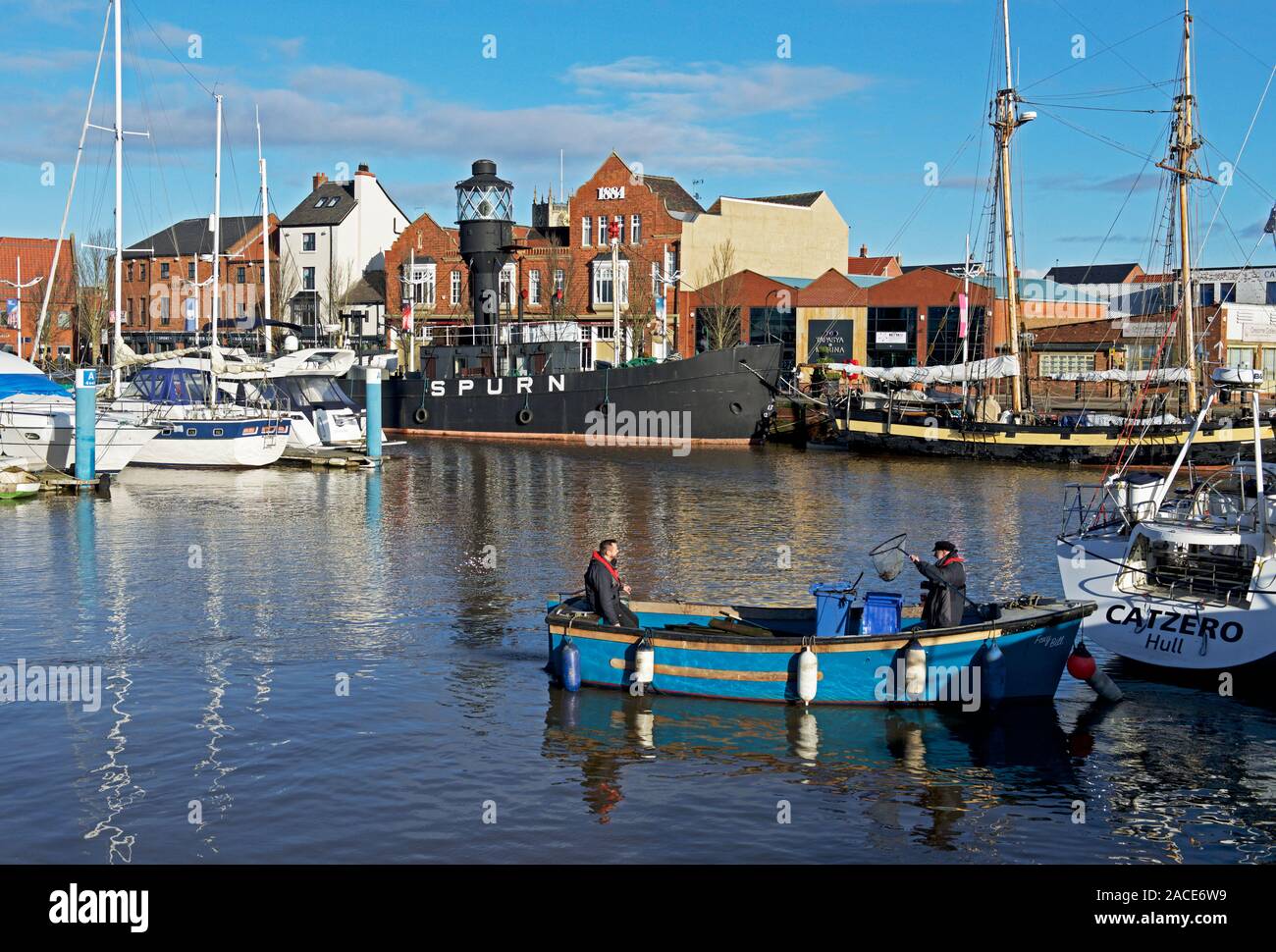 Due uomini in una piccola imbarcazione, sollevamento driftwood e lettiere fuori della marina, Hull, East Yorkshire, Inghilterra, Regno Unito Foto Stock