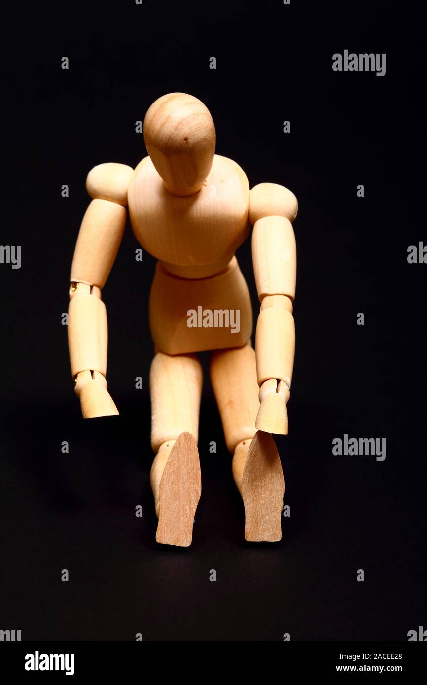 Immagine concettuale di un manichino di legno facendo sedere fino isolato su sfondo nero Foto Stock