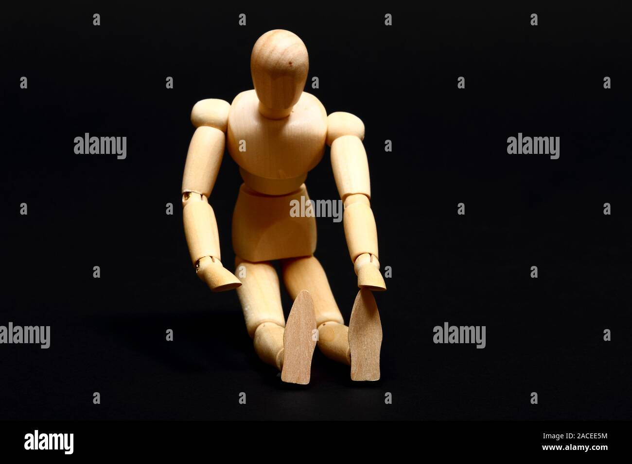 Immagine concettuale di un manichino di legno facendo sedere fino isolato su sfondo nero Foto Stock