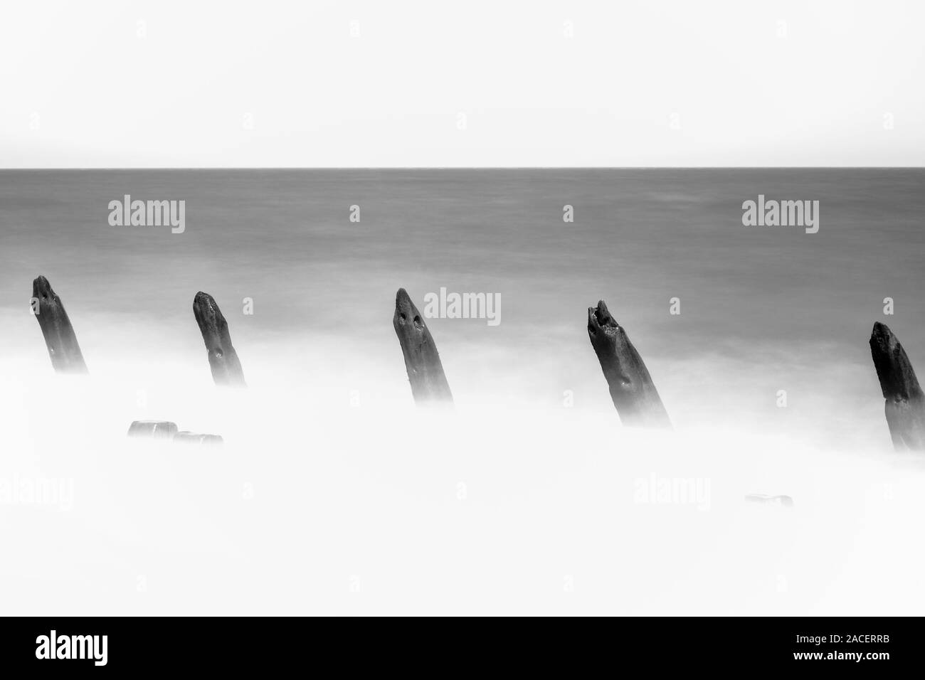 In bianco e nero lunga esposizione immagine del frangiflutti in legno sulla costa Est Inghilterra REGNO UNITO Foto Stock