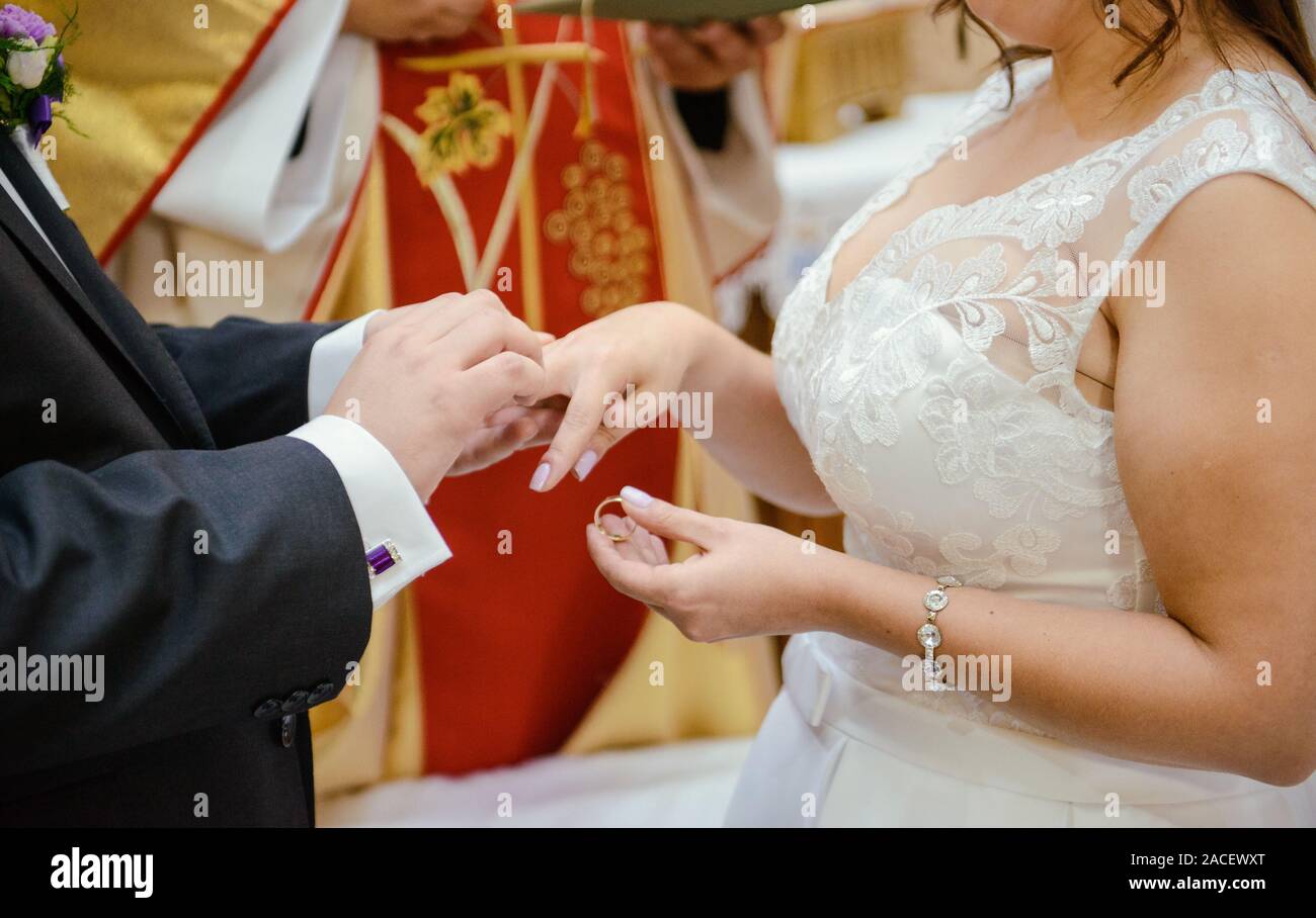 La sposa e lo sposo durante la cerimonia di nozze mettere gli anelli di nozze sulla loro dita. Foto Stock
