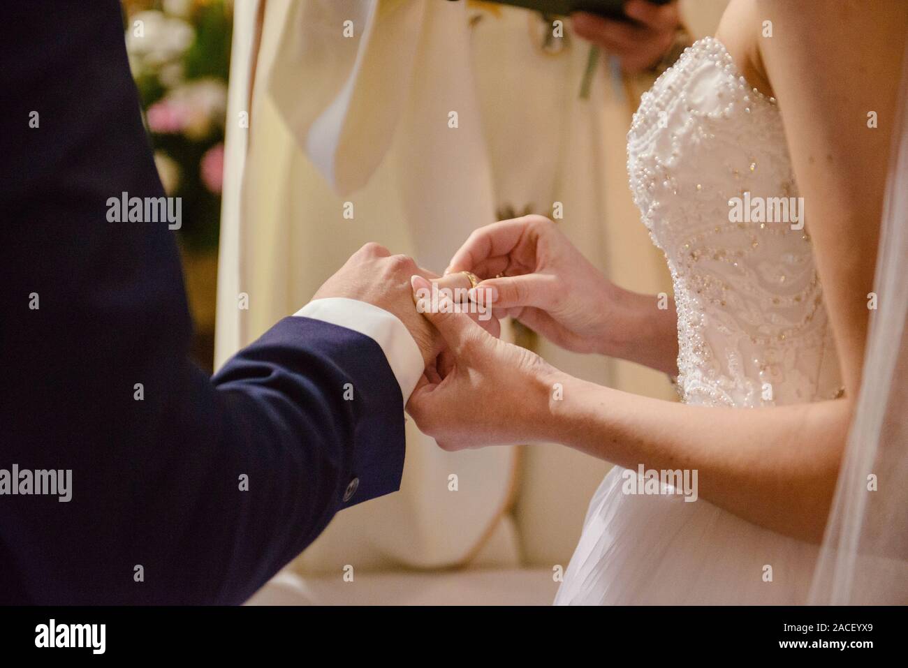 La sposa e lo sposo durante la cerimonia di nozze mettere gli anelli di nozze sulla loro dita. Foto Stock