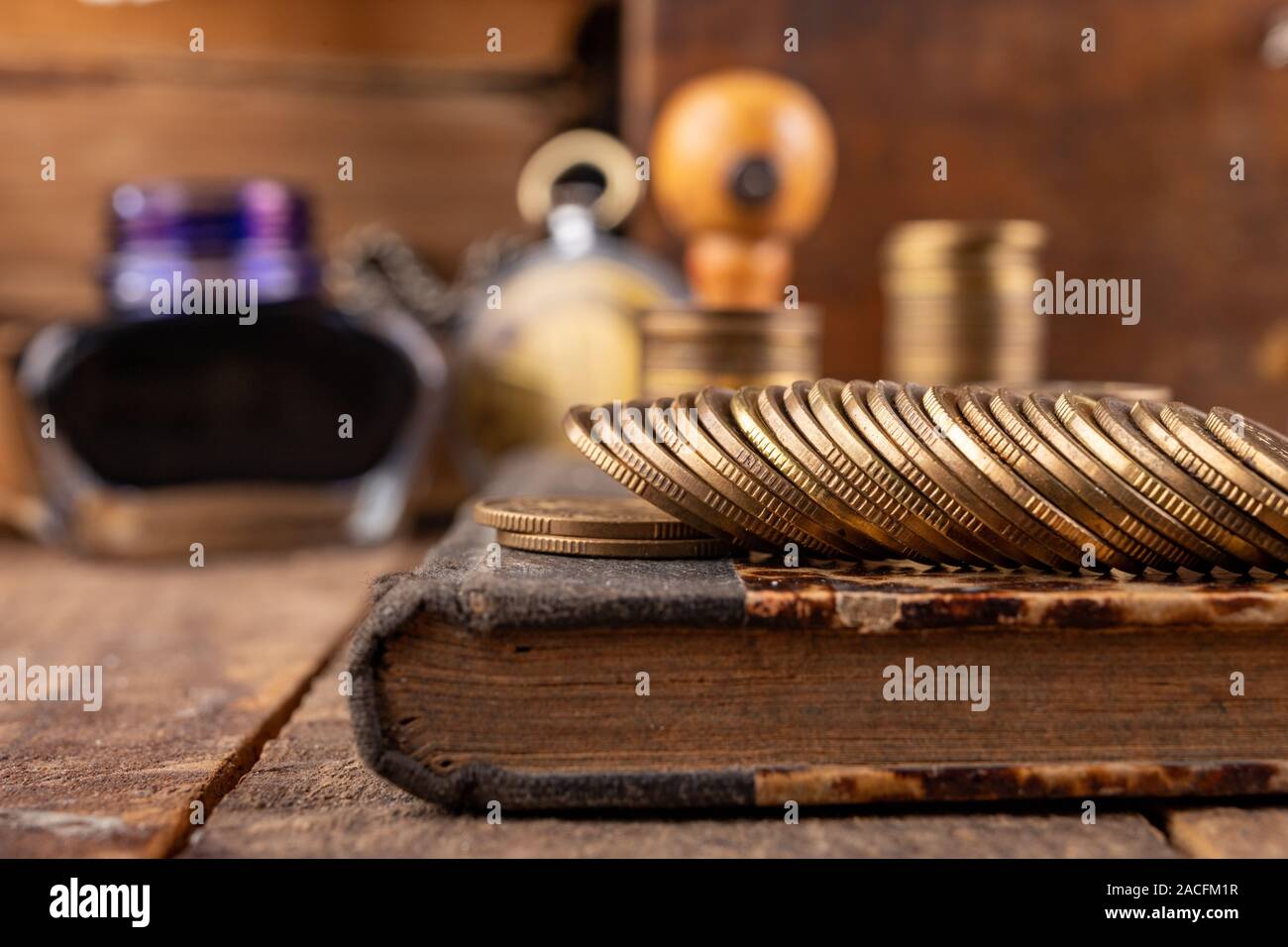 Monete metalliche disposte in barre su un vecchio libro. Un ragioniere sul posto di lavoro in una vecchia azienda. Sfondo scuro. Foto Stock