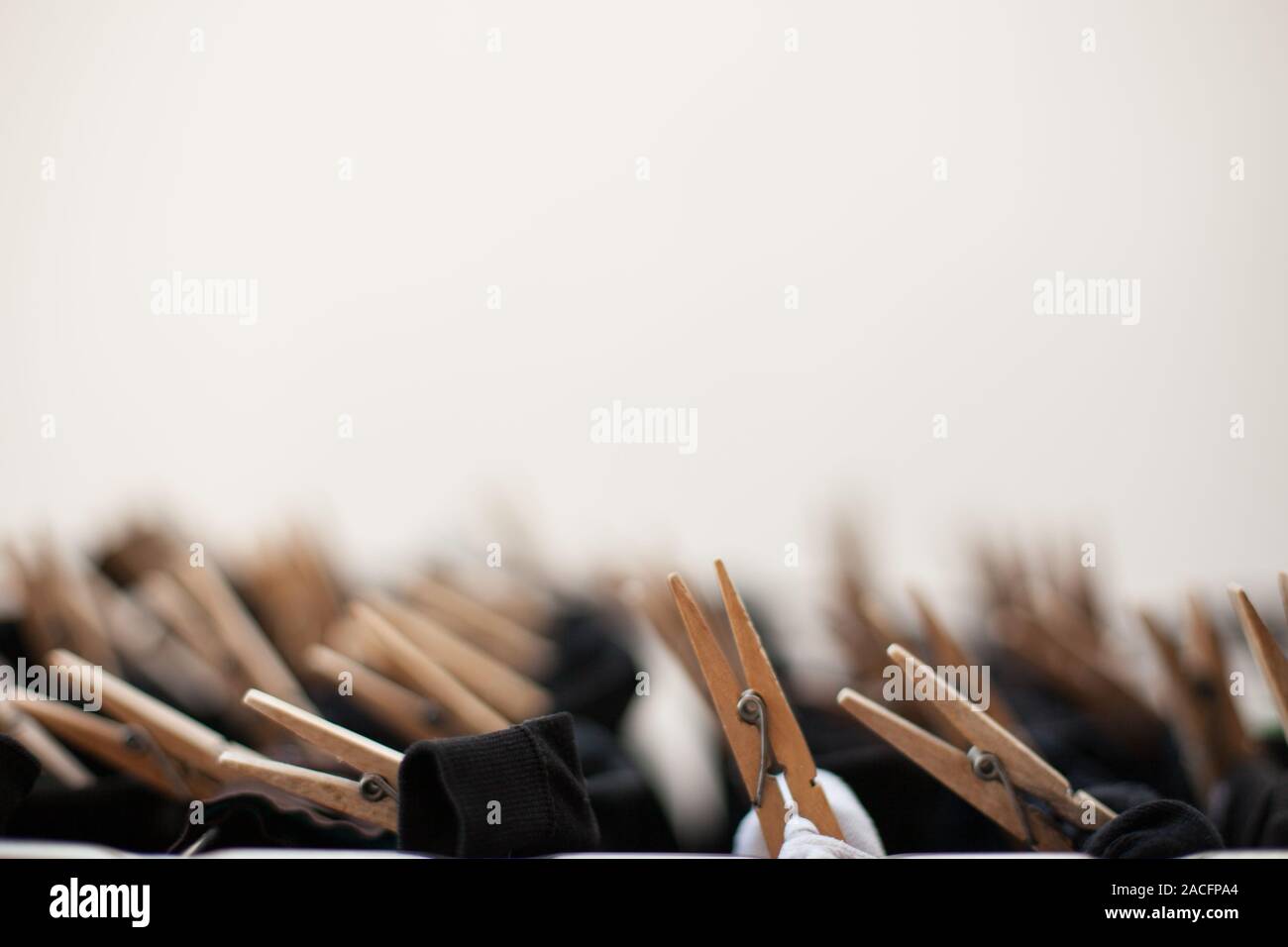 Clothespins in legno sul stendibiancheria con abiti neri appeso con sfondo non focalizzato Foto Stock