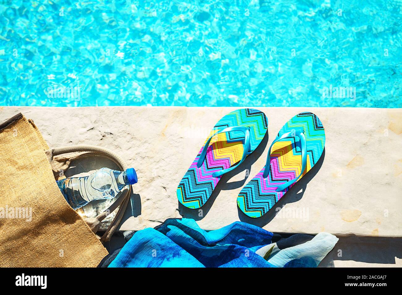 La piscina e il cappello di paglia, colorato flip flop, borsa di vimini, cappello di paglia, bottiglia con acqua ancora come sunny estate sfondo. Vacanze viaggi abbronzatura di Concetto di vacanza. Appartamento laico, vista dall'alto, vicino. Foto Stock