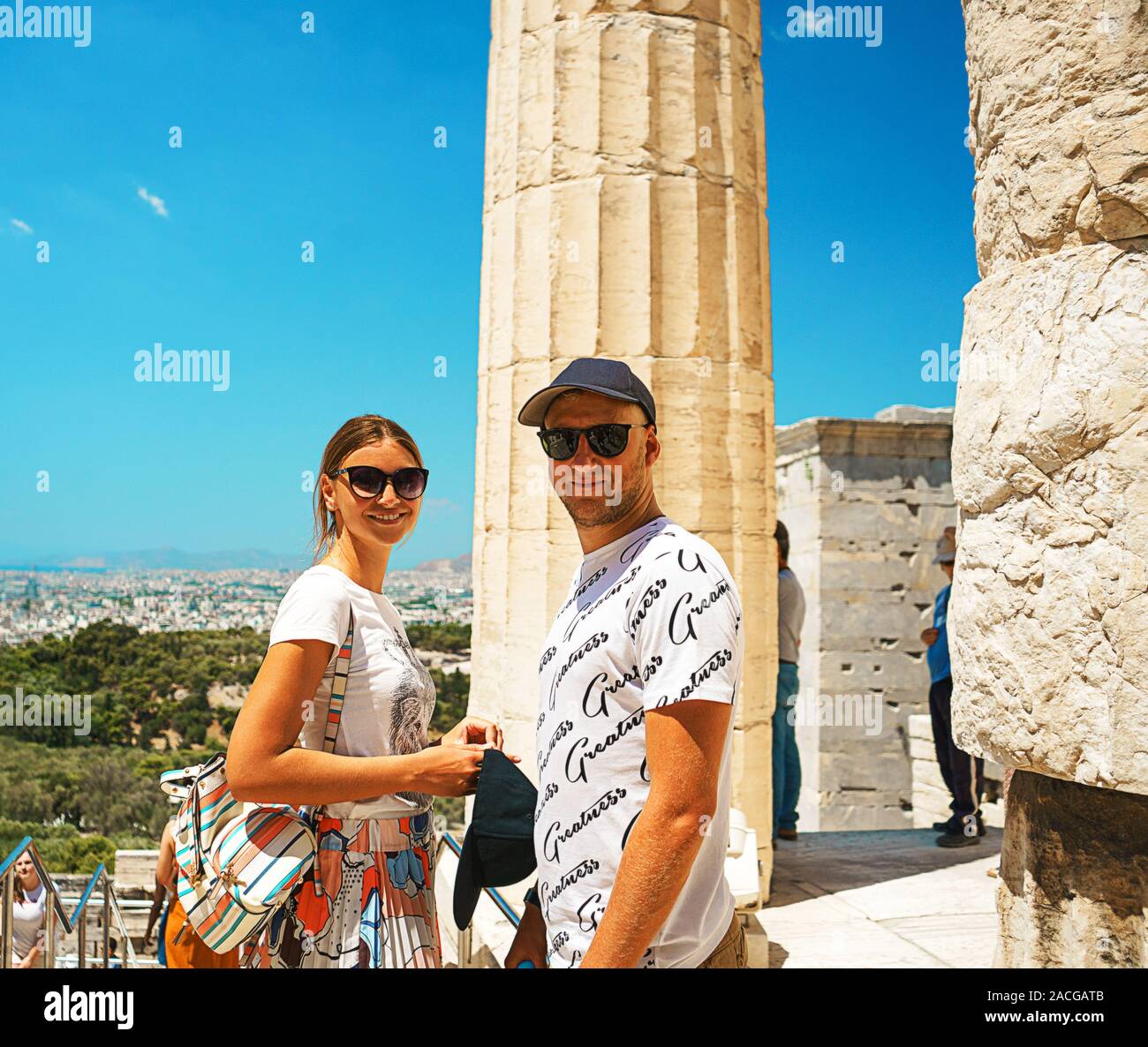 Giovane è felice sul tempio antico Partenone dell'Acropoli di Atene Grecia e cielo blu sullo sfondo. Coppia è divertente esplorare posti molto belli. Le migliori destinazioni di viaggio. Foto Stock