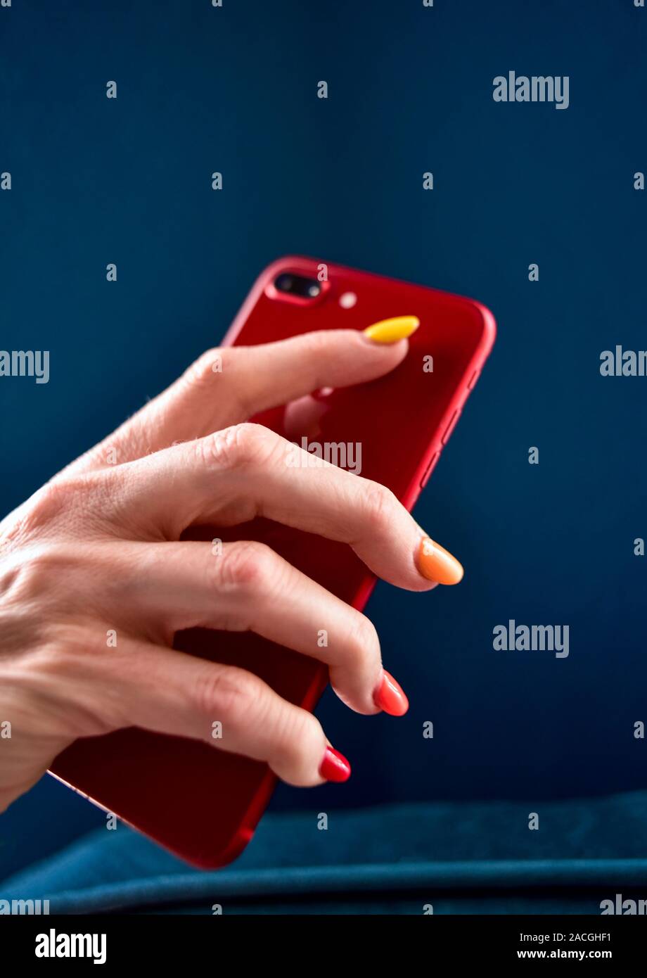 Una donna in possesso di un telefono cellulare con multi-colore le unghie. Foto Stock