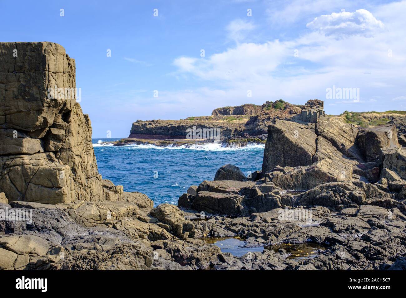 Vista su basalto formazioni rocciose e le piscine di roccia verso il mare a Bombo cava di capezzagna, New South Wales coast, Australia Foto Stock