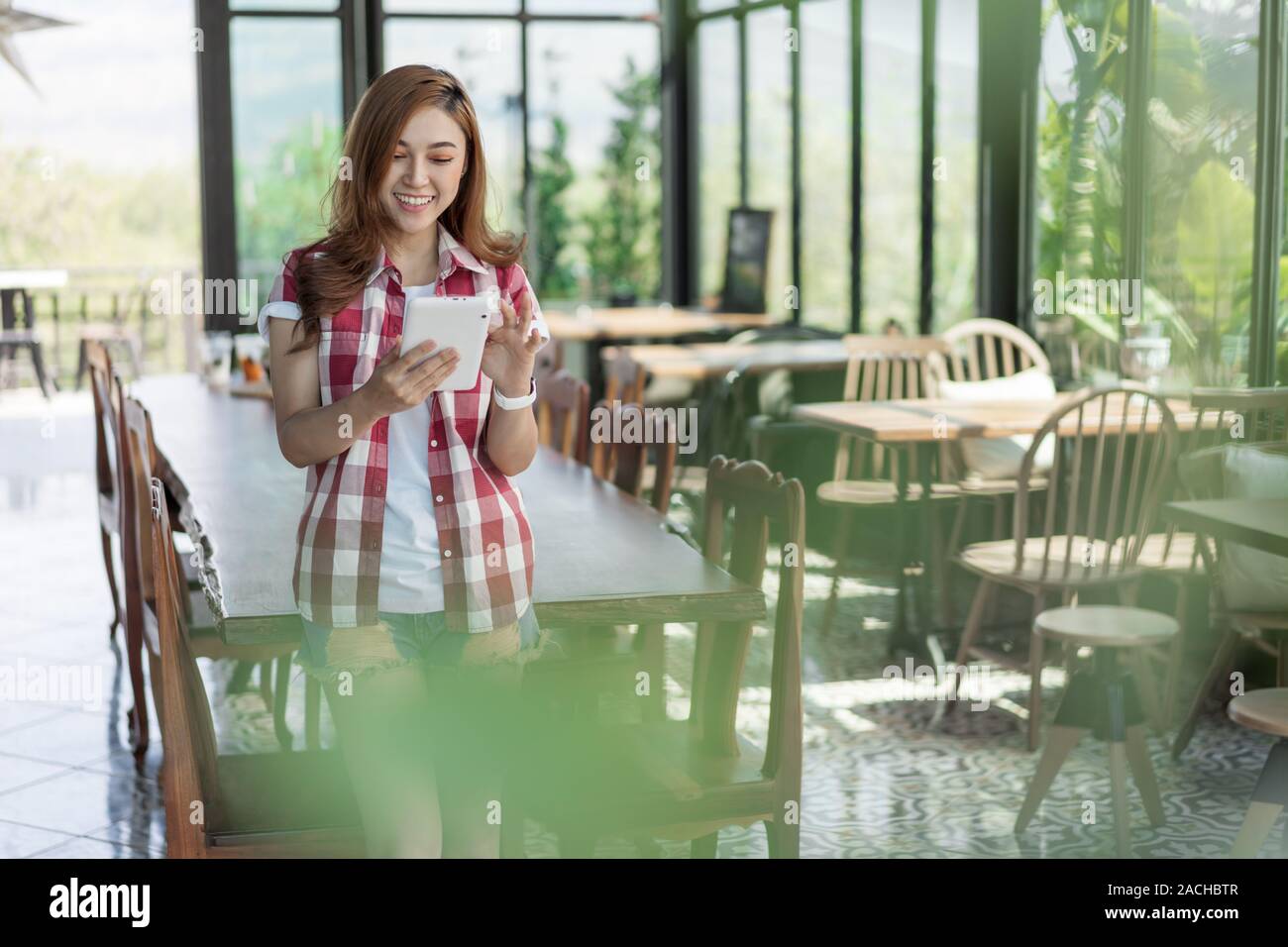 Donna felice con tavoletta digitale in un cafe Foto Stock