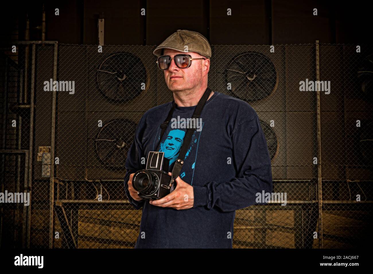 Fotografo con una telecamera analogica, occhiali da sole ed un cappello. Foto Stock