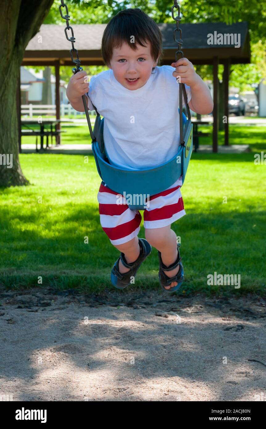 Little Boy giocando sul parco giochi presso il parco della città in una calda giornata estiva. Foto Stock