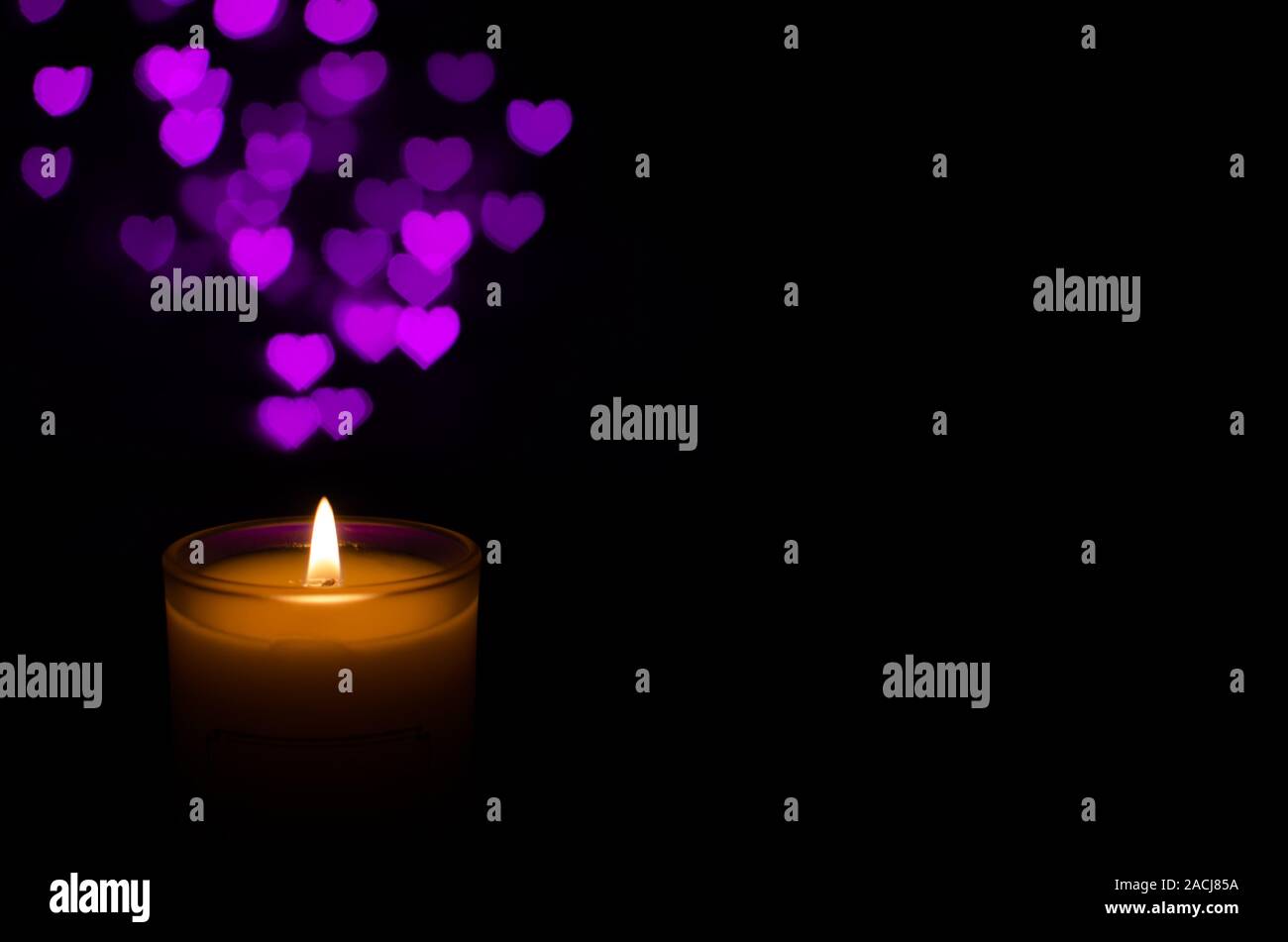 Bianco vetro aromatico candela con la fiamma e amore bokeh di fondo di forma su sfondo scuro per il giorno di San Valentino. Foto Stock