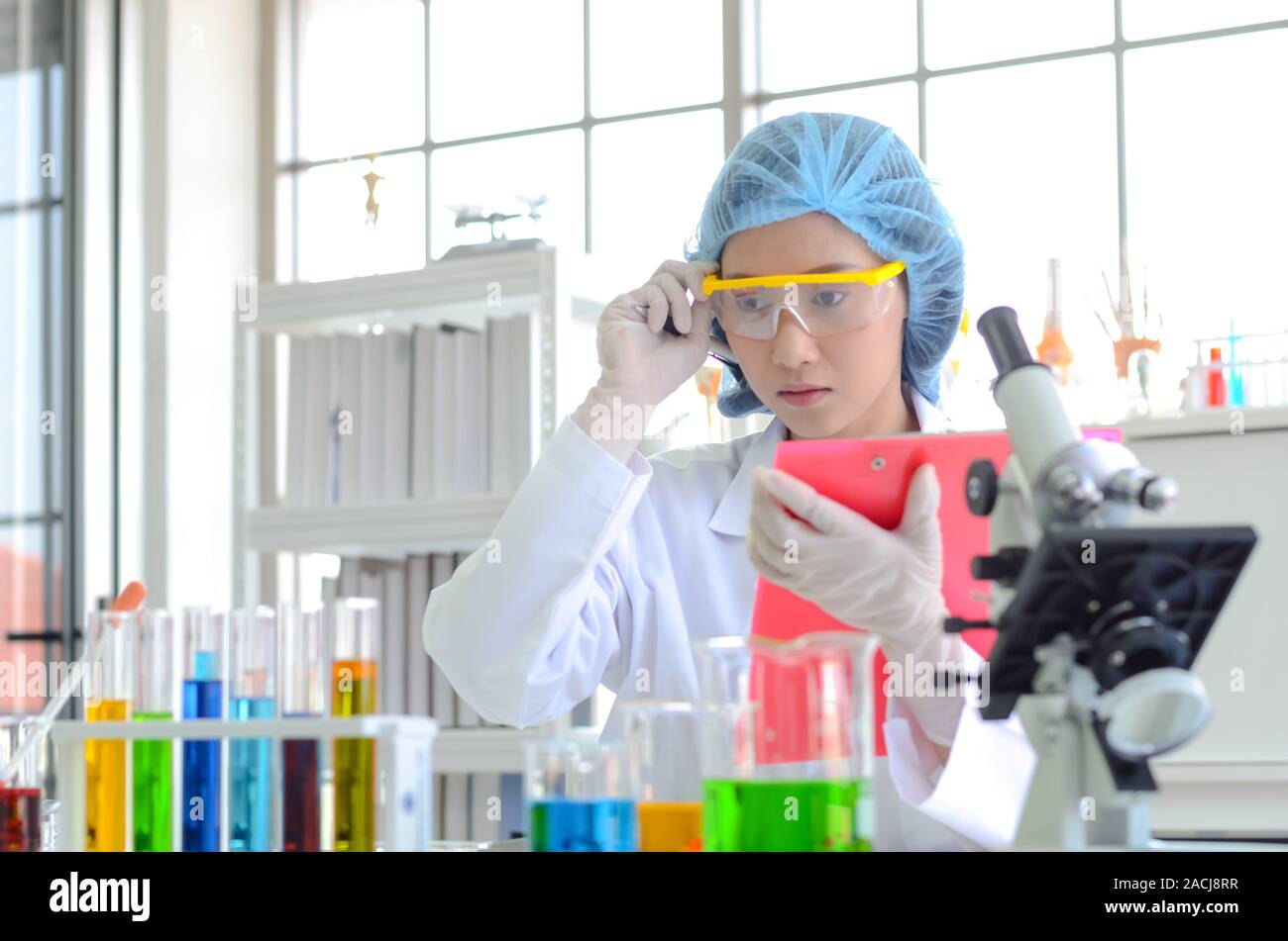La scienziata nel laboratorio di fare esperimenti con liquido chimico e facendo e lista di controllo per registrare i dati dei test in laboratorio. Foto Stock