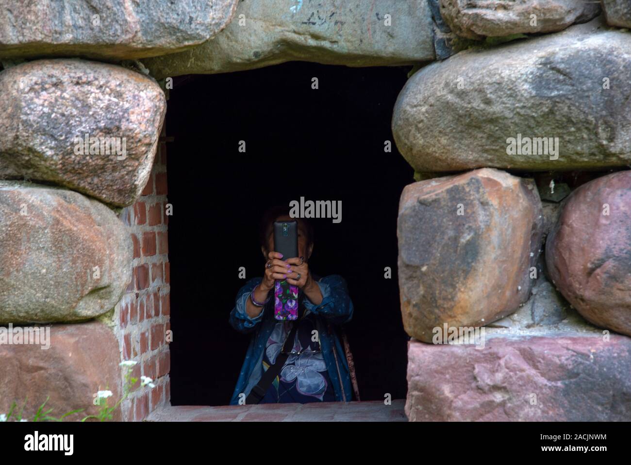 Una donna prende una foto sul telefono in piedi in apertura della parete. Foto Stock