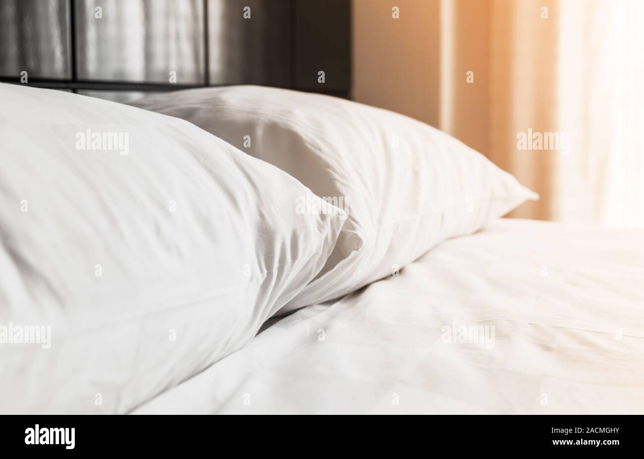 Cuscini bianchi i laici a un letto vuoto vicino alla finestra con la luce del mattino, foto di sfondo con il fuoco selettivo Foto Stock