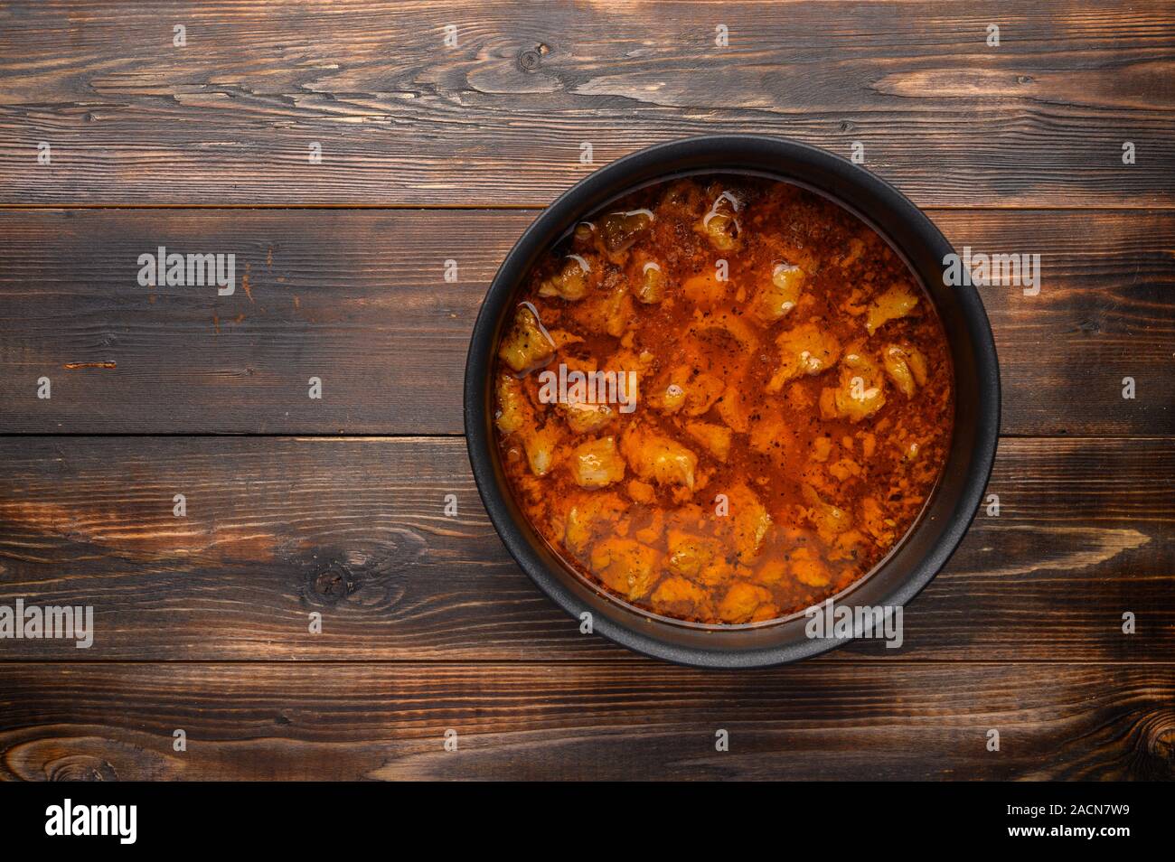 In casa tradizionale gulasch ungherese piatto in un tegame contro uno sfondo di legno Foto Stock