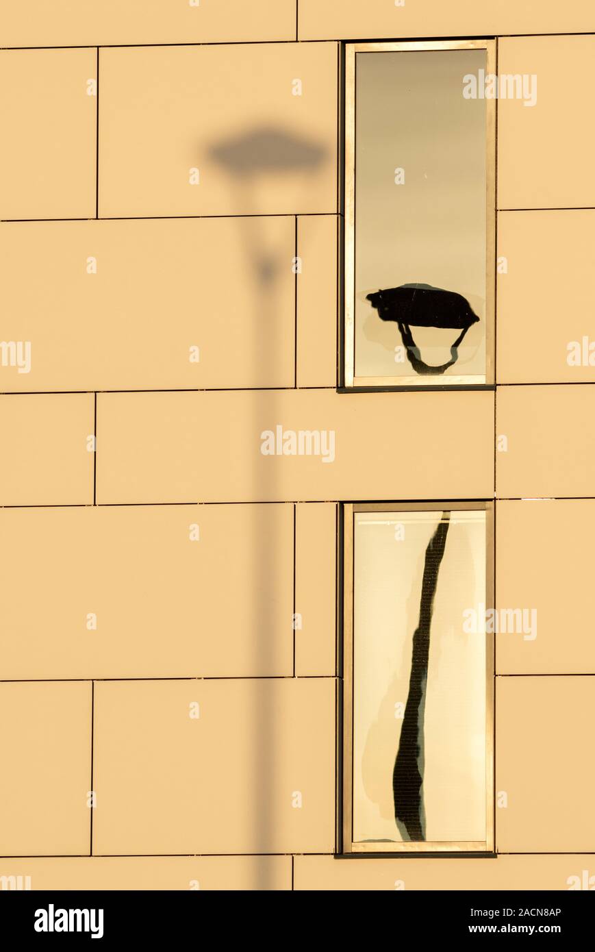 Lampada posta in ombra sul muro con il suo riflesso in una finestra come creativa composizione artistica astratta. Foto Stock