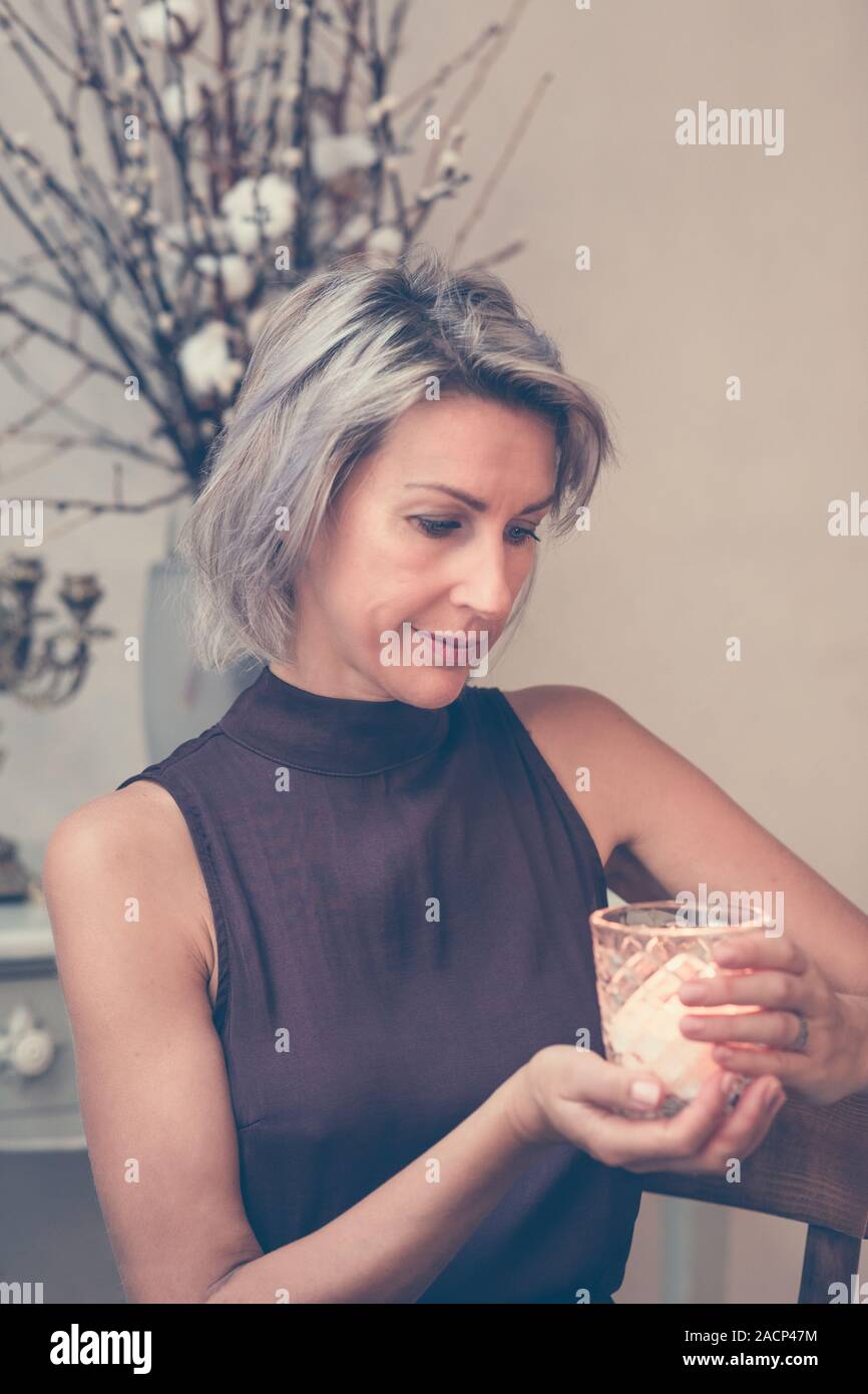 Tonica immagine della bella bionda signora seduta nel bar o ristorante Candela di contenimento Foto Stock