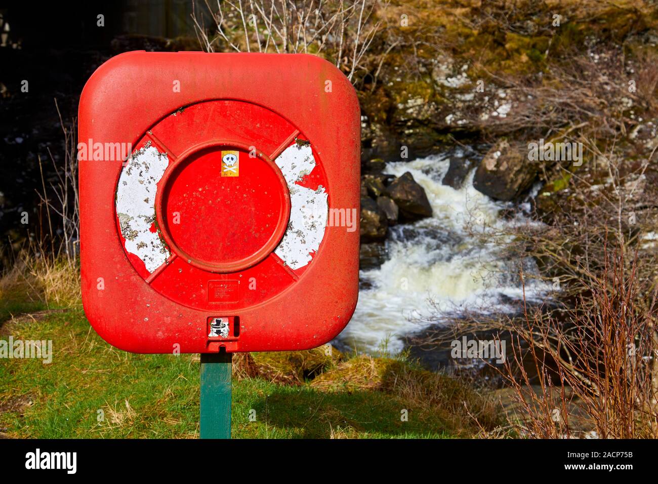 Salvagente in un involucro di plastica rosso accanto a scorrimento veloce acqua, Strath of Orchy, Scozia Foto Stock