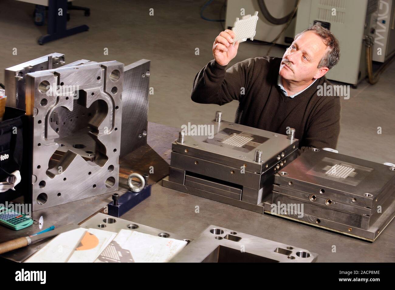 Lo stampaggio ad iniezione. Lavoratore azienda progettate con precisione stampati ad iniezione di componenti in plastica. Fotografato a Saint Ouen l'Aumone, Parigi, Francia. Foto Stock