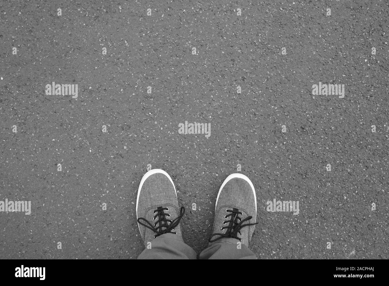 Piedi in scarpe di tela permanente sulla strada - piede selfie dal punto di vista personale punto di vista - asfalto sfondo con spazio di copia Foto Stock