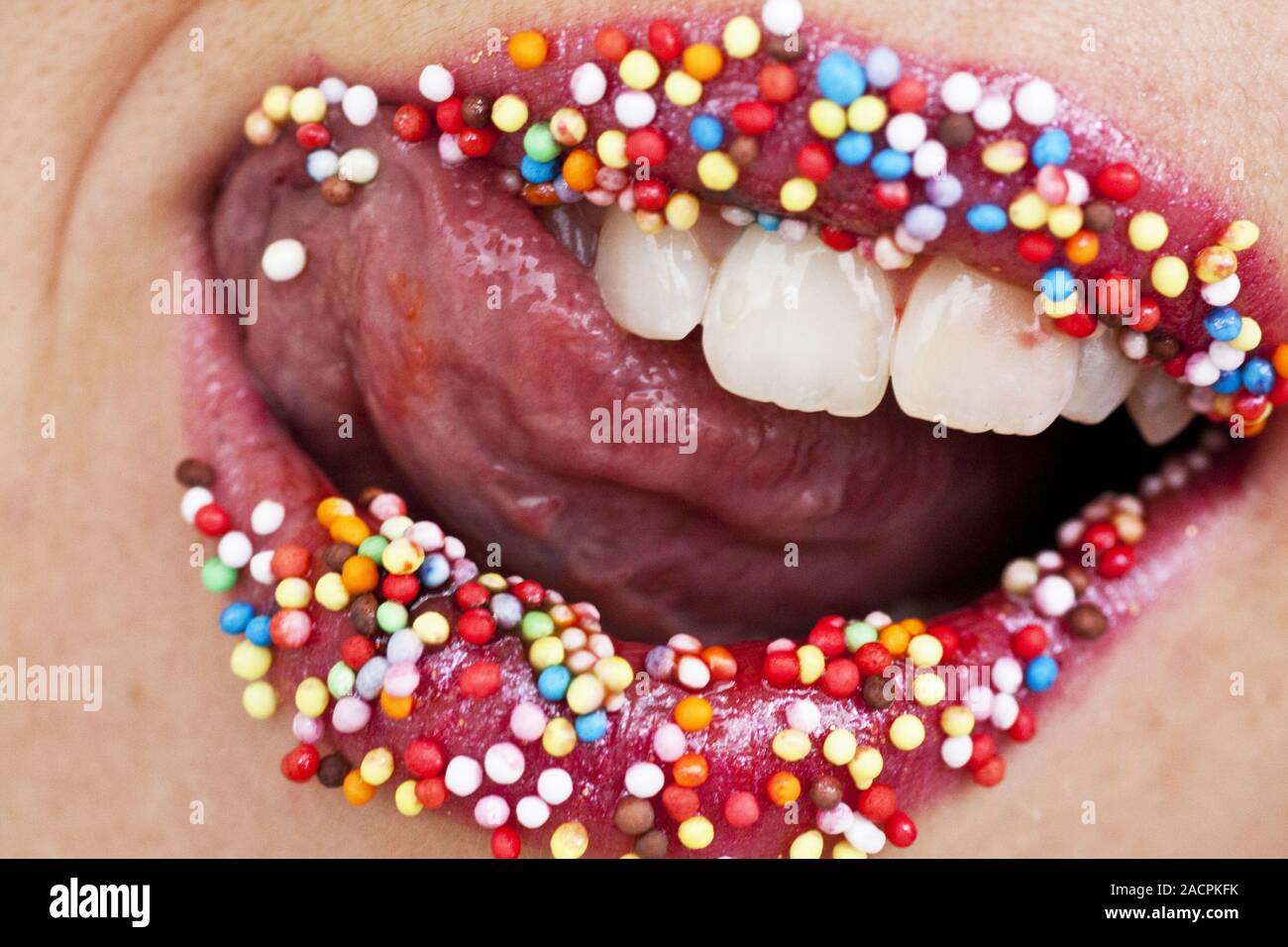 Caramelle colorate sulle labbra rosse Foto Stock