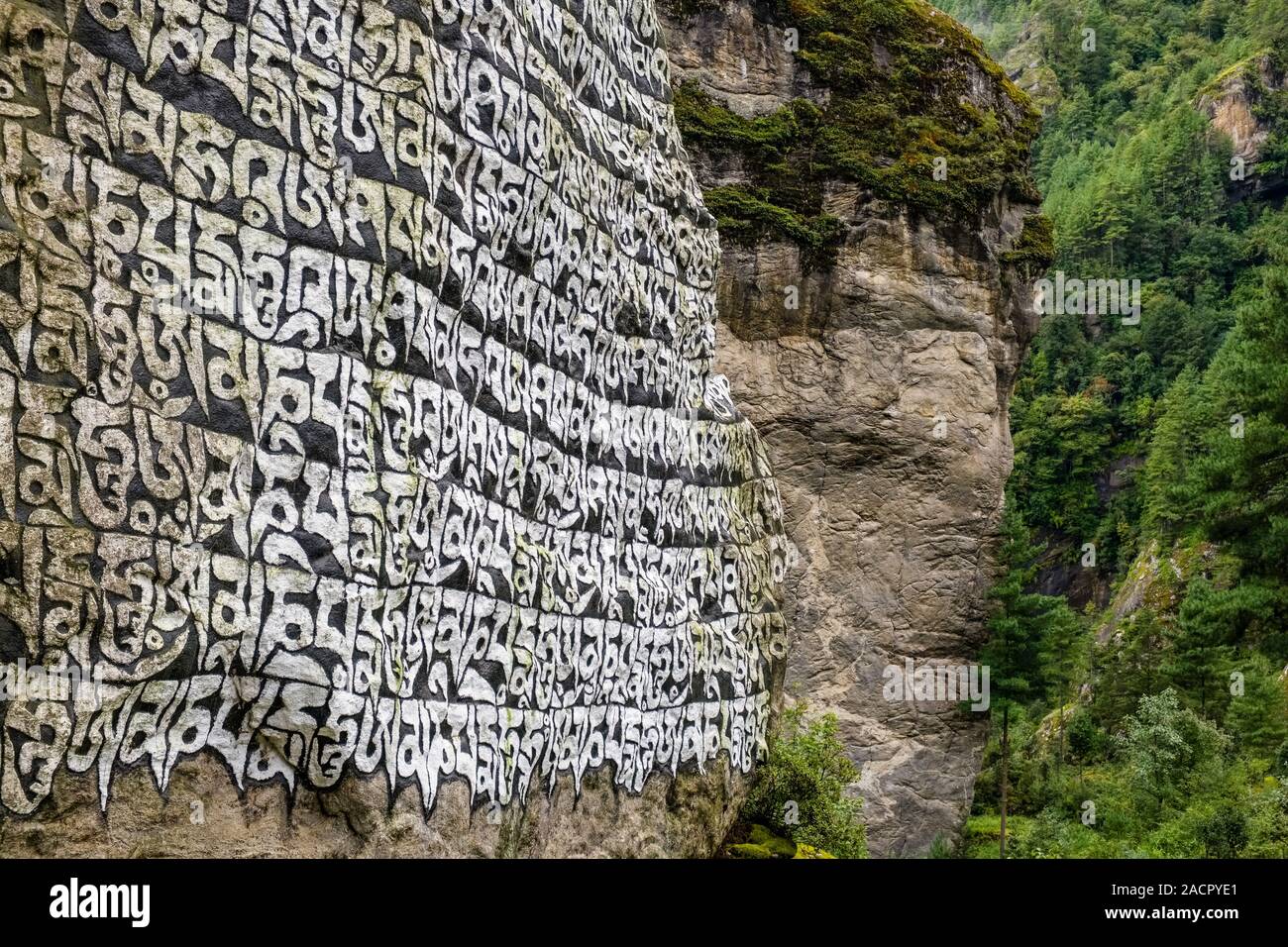 Grandi Mani di pietra con inciso il mantra tibetano OM MANI PADME HUM, situato all'entrata del villaggio Foto Stock