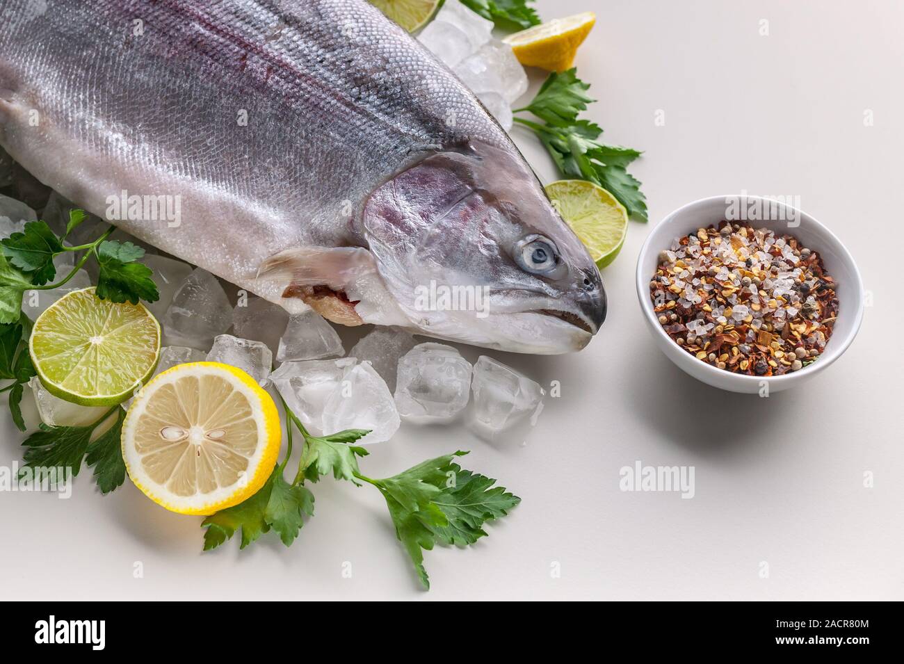Close-up materie wild trout. Spezie, limone, prezzemolo fresco e il ghiaccio. Sfondo chiaro. Alimenti biologici Foto Stock