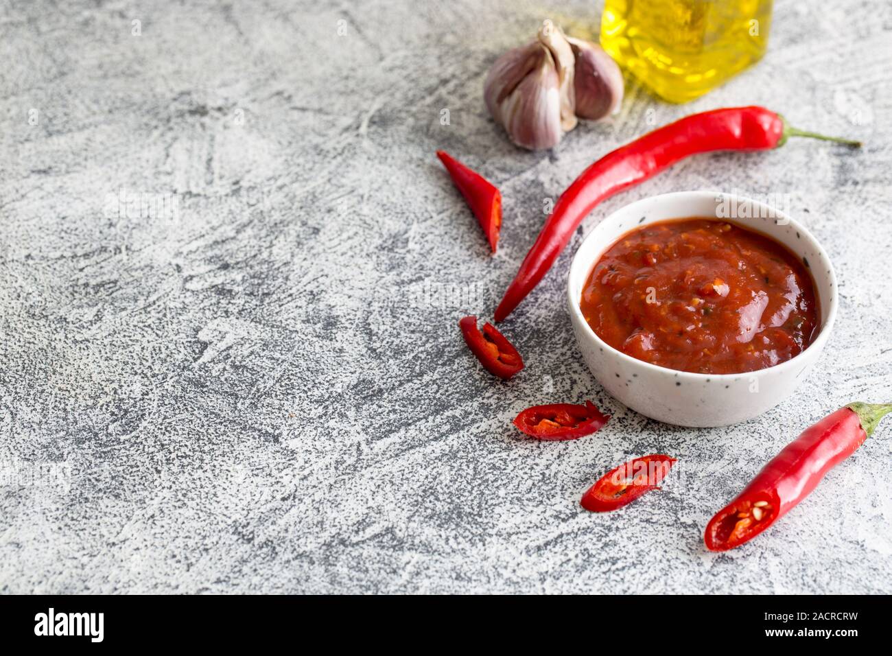 Ketchup con peperoncino e aglio su un cemento grigio Sfondo con spazio di copia Foto Stock