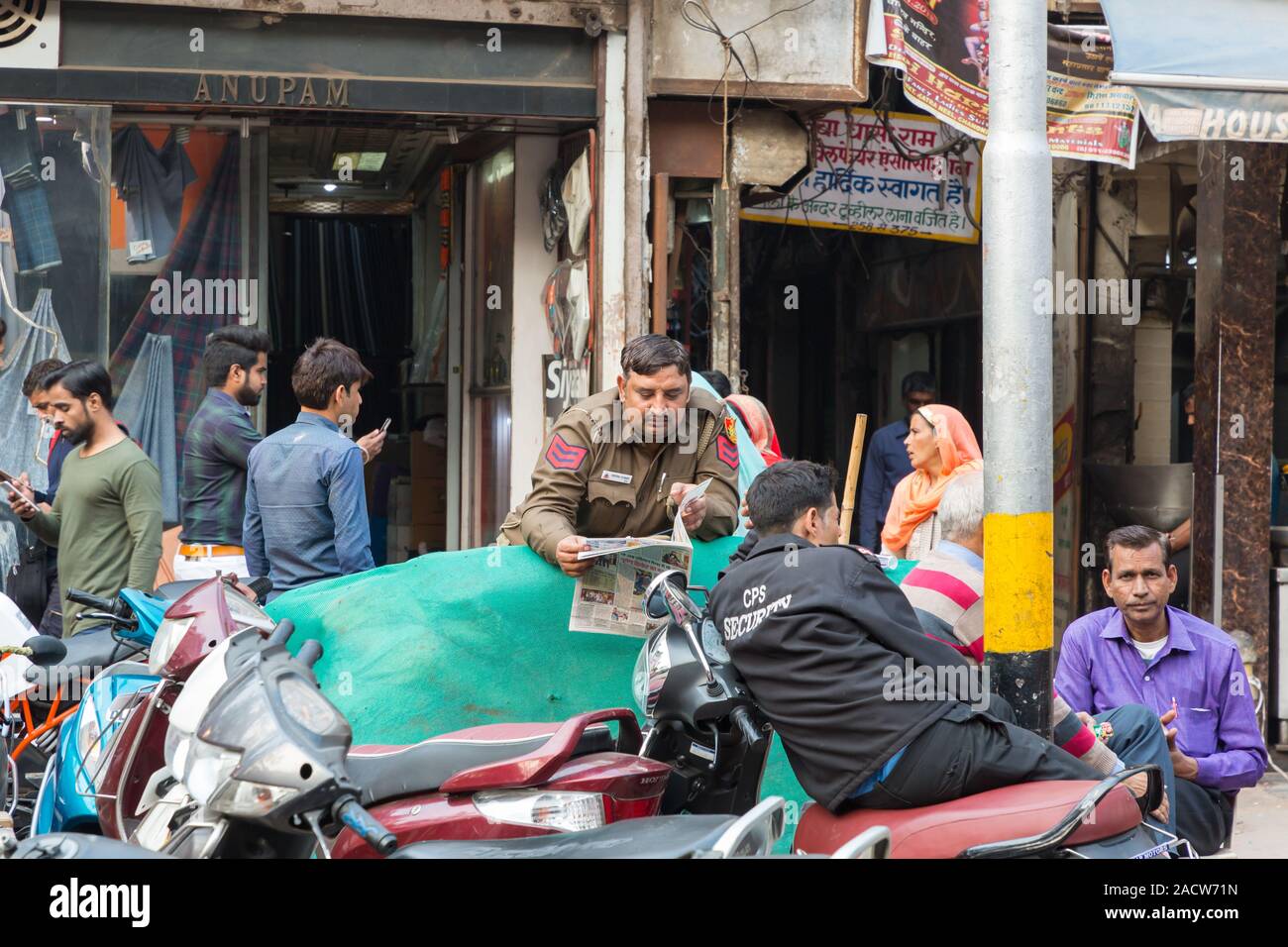 La gente e la polizia indiana personale leggendo il giornale a Chandni Chowk Vecchia Delhi Foto Stock