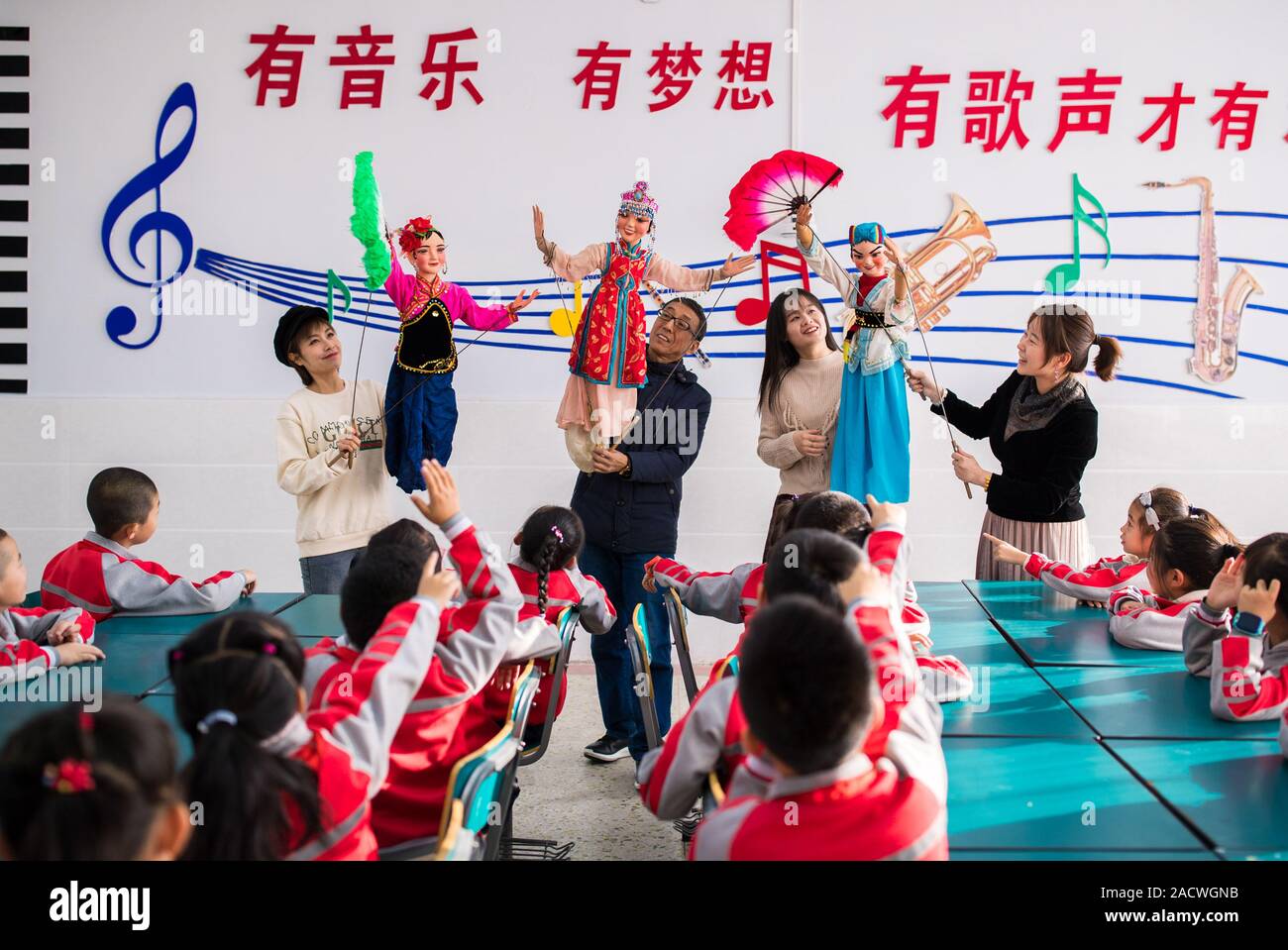 La partecipazione di musicisti locali il dramma dei burattini troupe insegnare ai giovani studenti come operare burattini durante una presentazione e insegnamento in una scuola primaria in Ho Foto Stock