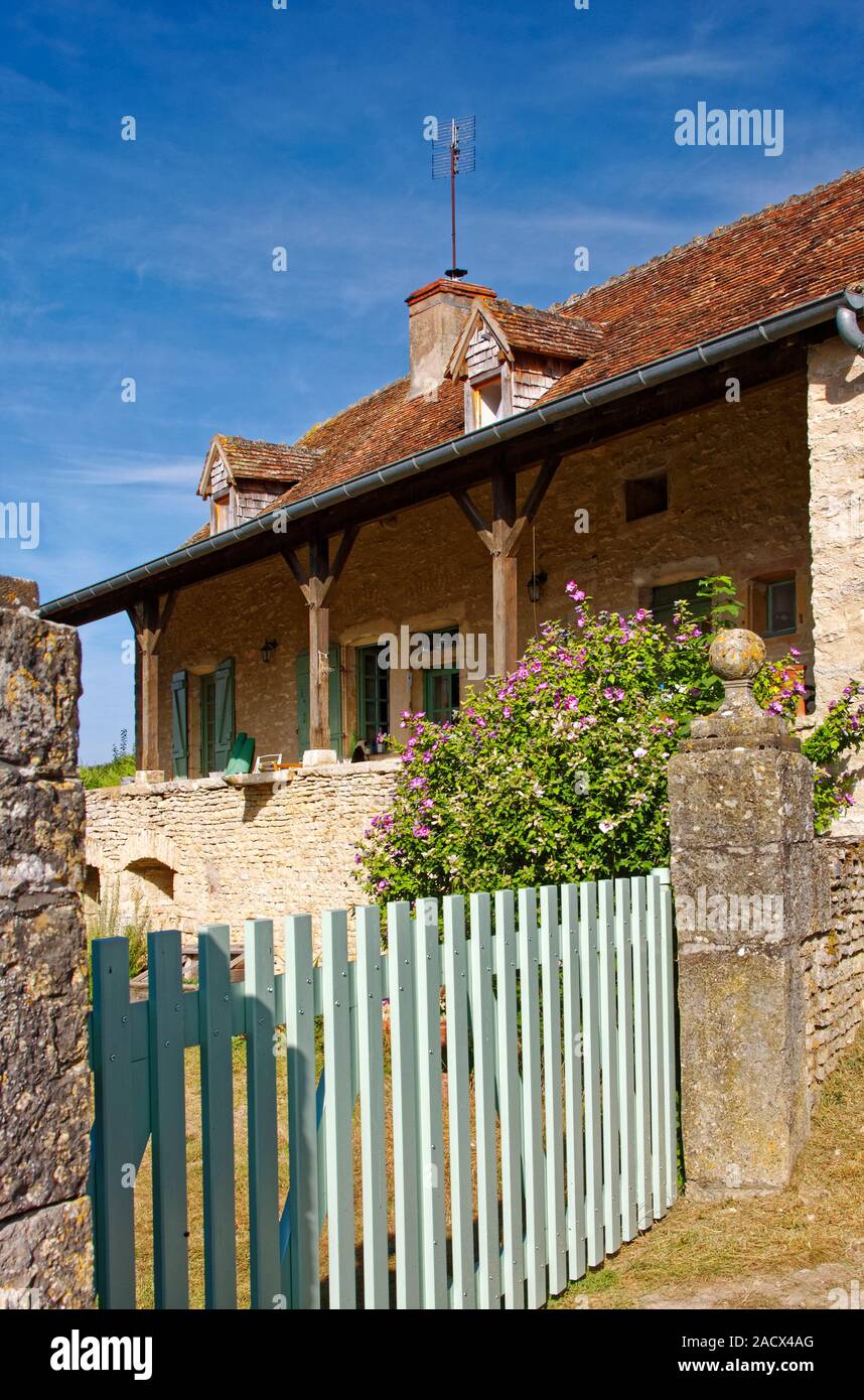 Vecchia casa di pietra, recinzione blu, abbaini, portico, fiori, antenna TV, Saône-et-Loire, Borgogna, Macon, Francia, estate, verticale Foto Stock