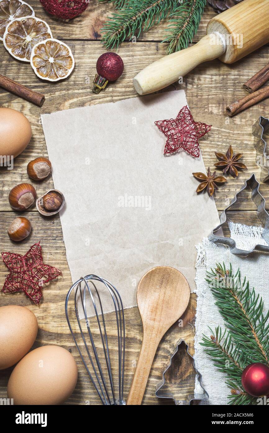 Il vecchio foglio di carta con gli ingredienti e gli utensili per la cottura dei biscotti di Natale e decorazioni intorno sul vecchio tavolo in legno. Vista superiore della cucina rurale la Foto Stock