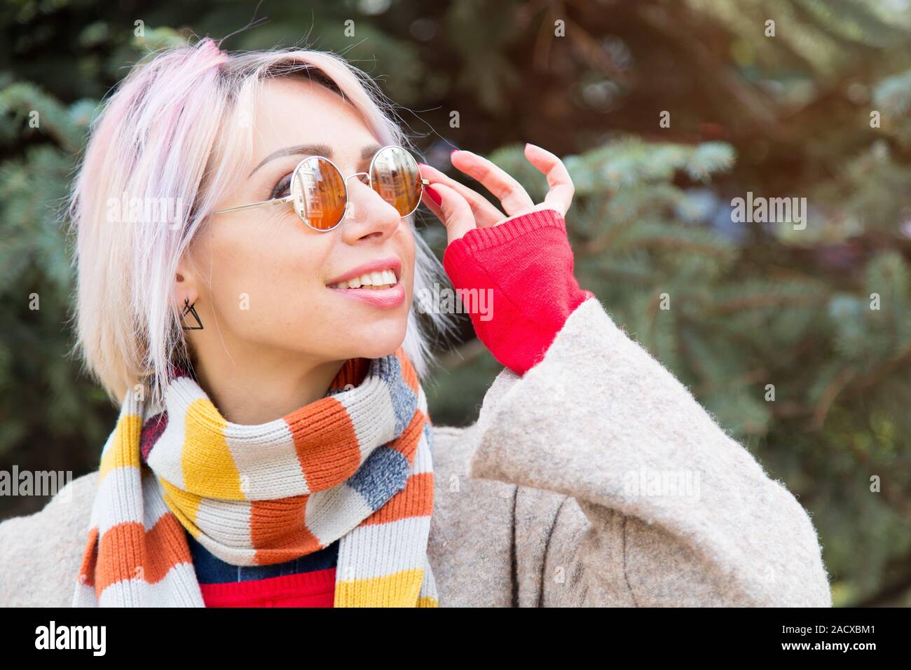 Giovane donna in occhiali da sole su uno sfondo di abete. Stile di vita ritratto all'aperto. Foto Stock