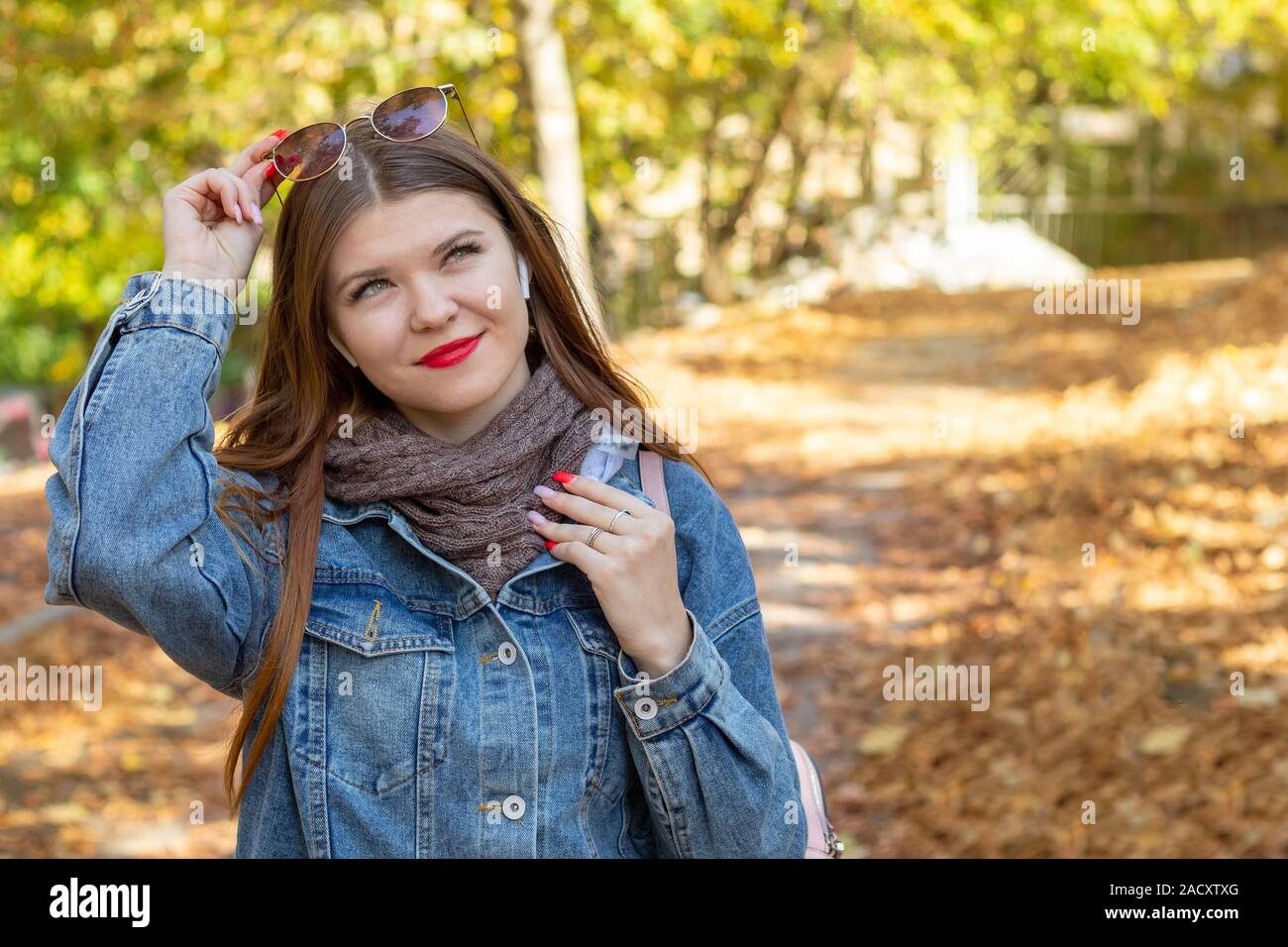 Una giovane donna ascoltare musica in un parco d'autunno. Autunno a piedi nel parco. I sogni e la musica. Foto Stock