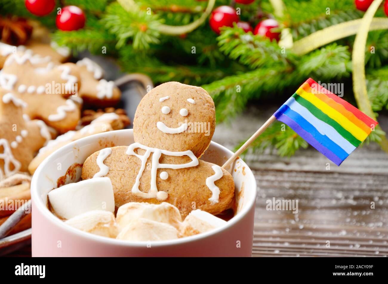 Rosa la tazza con il cioccolato caldo marshmallows e gingerbread man con bandiera arcobaleno sullo sfondo del ramo di abete e il vassoio con i cookie Foto Stock