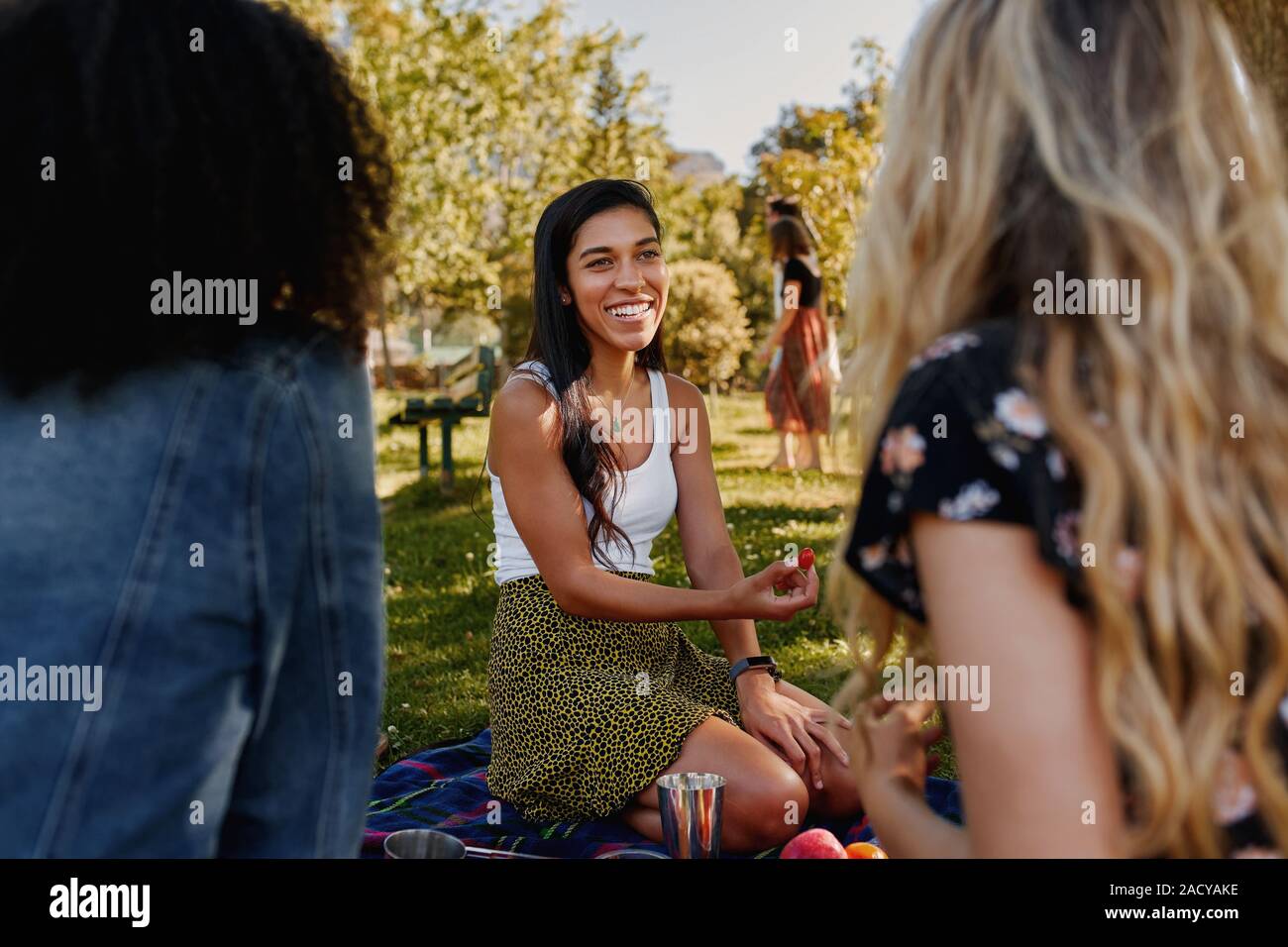 Ritratto di un felice giovane femmina amici seduti sul prato verde di trascorrere del tempo insieme nel parco - gruppo di amici di sesso femminile avente un picnic in Foto Stock
