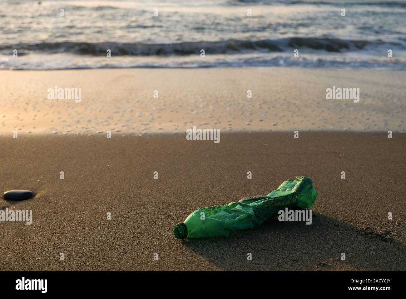 Verde bottiglia di plastica sulla costa del mare,Tramonto luce d'oro,inquinato il concetto di ecosistema Foto Stock