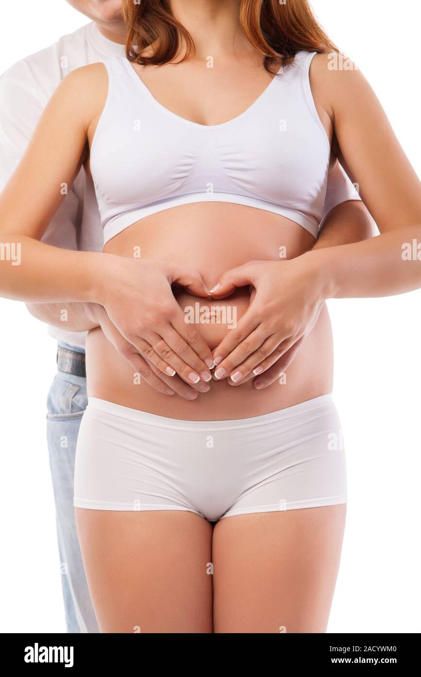 Donna incinta e uomo cuore di formatura sul baby bump Foto Stock