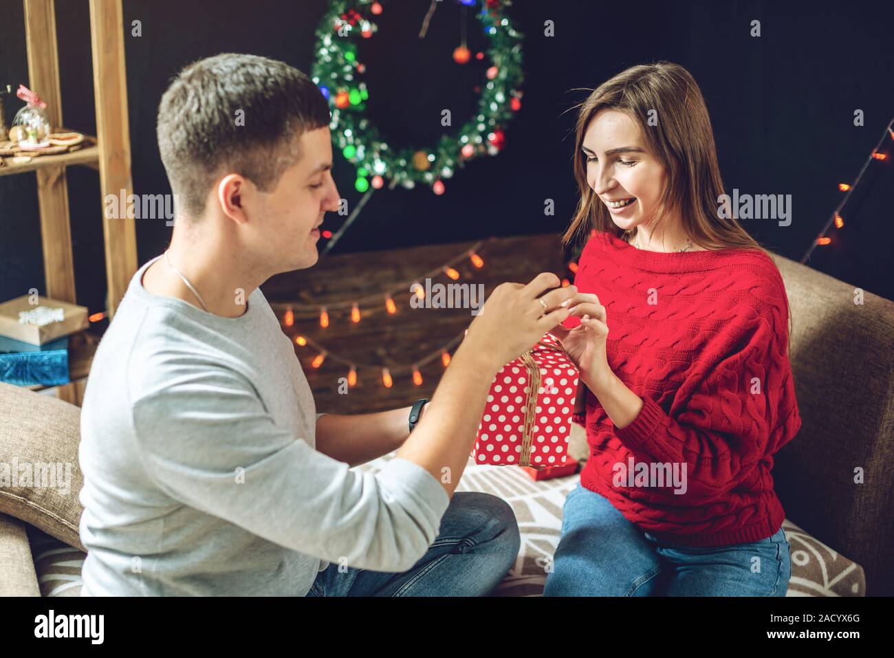 Uomo bello marito dà la sua moglie un regalo a sorpresa box. Una coppia  sposata si festeggia il Natale e il nuovo anno in un accogliente ambiente  domestico Foto stock - Alamy