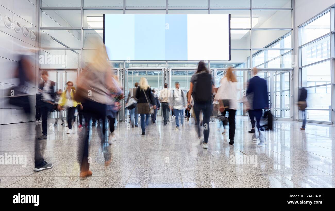 Molti anonimo i visitatori della fiera lungo andare sotto grandi spazi pubblicitari Foto Stock